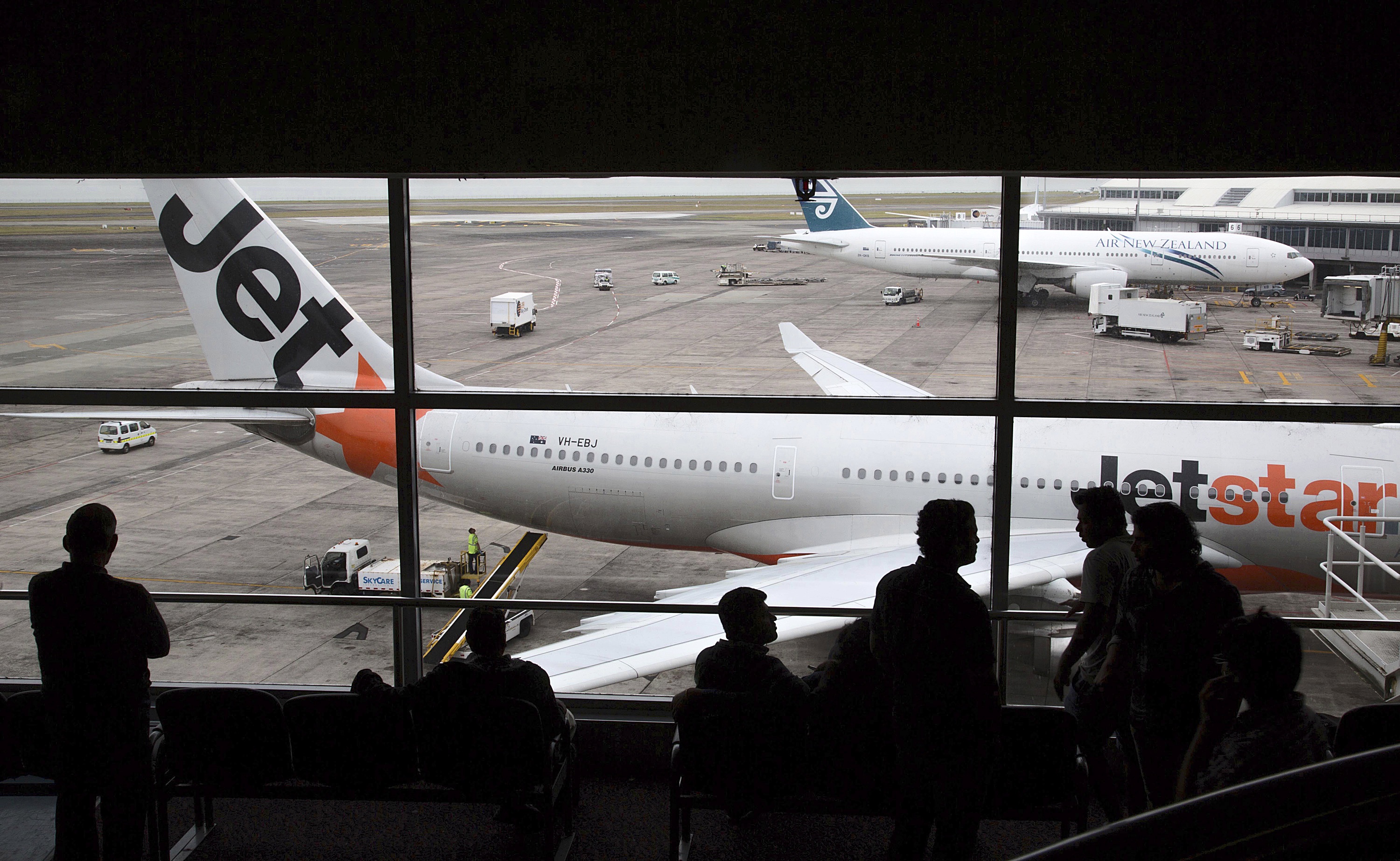 More choice: Travelers wait in a departure lounge as a Jetstar Airways aircraft, front, and an Air New Zealand Ltd. aircraft stand on the tarmac at Auckland International Airport in Auckland in 2012. Photo / Getty Images