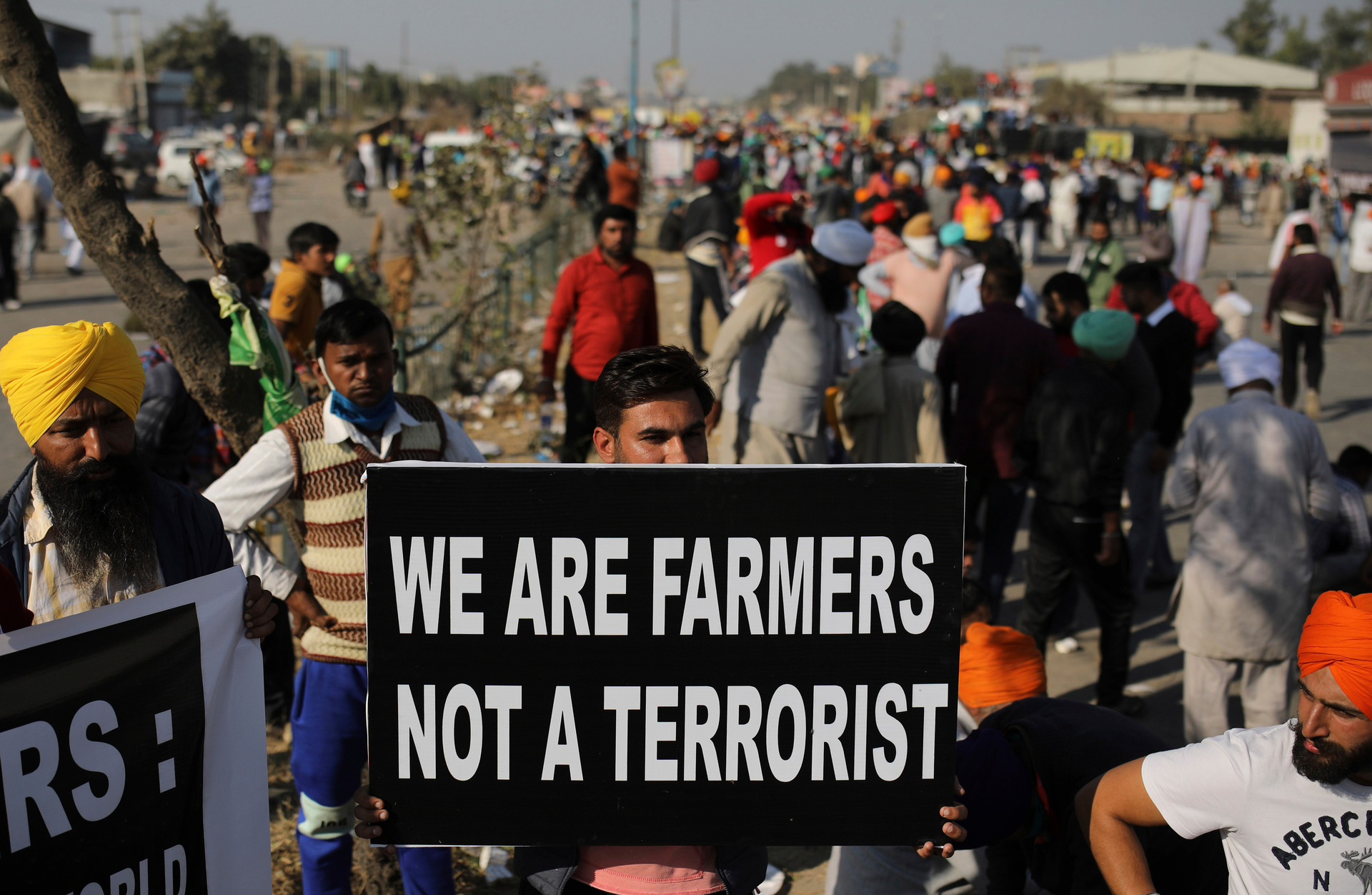 A farmer holds a sign on a major highway, blocking traffic as they protest new farm laws, at the Delhi-Haryana state border, India. Photo / AP
