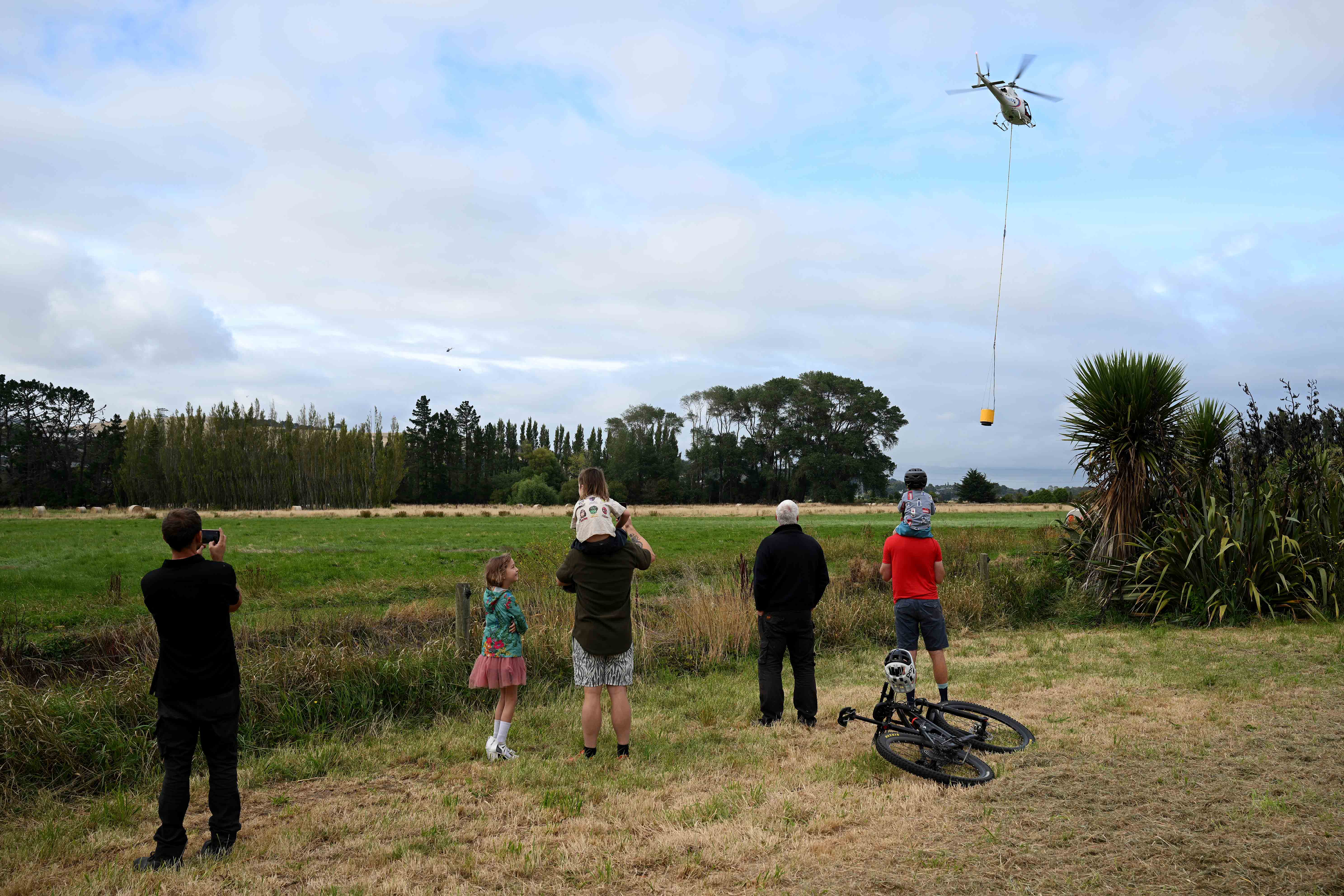 Helicopters prepare to take on day four. A large fire has broken out in Chritchurch’s Port Hills causing mass evacuations. 17 February 2024 New Zealand Herald Photograph by Joe Allison