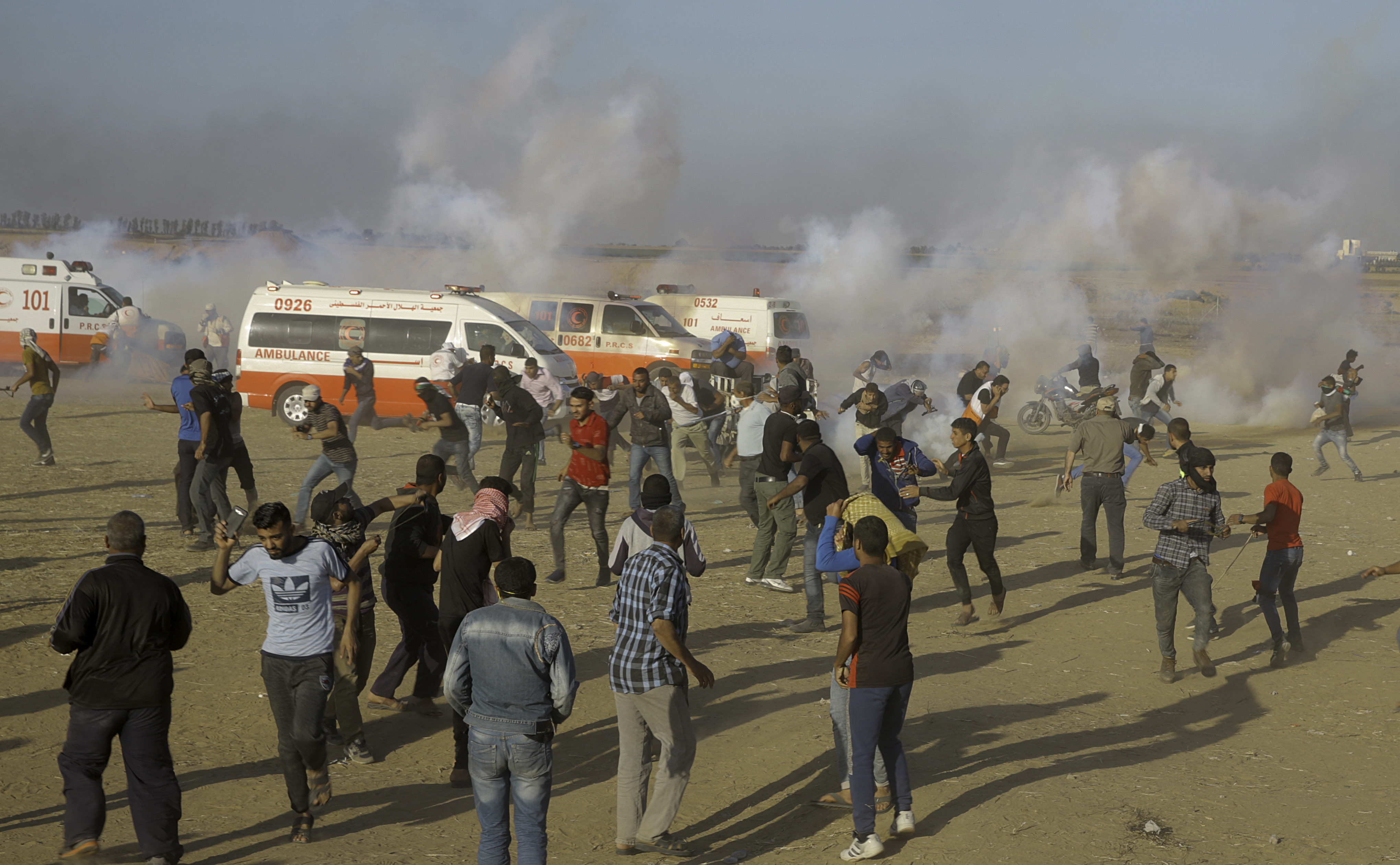Palestinian protesters run for cover from teargas fired by Israeli troops during a protest at the Gaza Strip's border with Israel. Photo / AP 