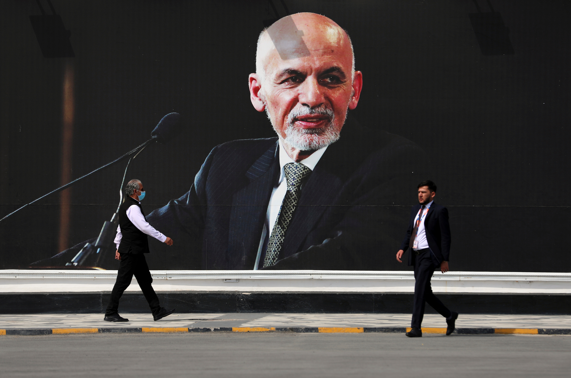 People walk near a mural of President Ashraf Ghani at Hamid Karzai International Airport, in Kabul, Afghanistan. Photo / AP