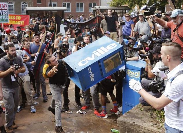 White nationalist demonstrators clash with a counter-demonstrator as he throws a newspaper box at the entrance to Lee Park in Charlottesville. Photo: AP Photo/Steve Helber