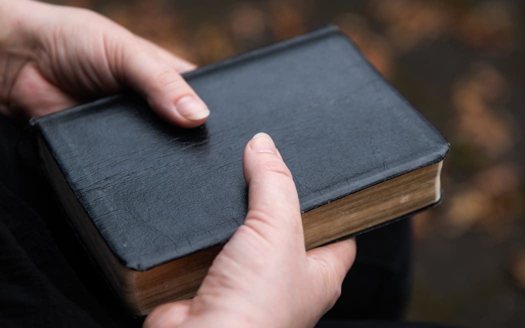A young woman holds her childihood bible, the New World Translation of the Holy Scriptures. Photo / Cole Eastham-Farrelly, RNZ