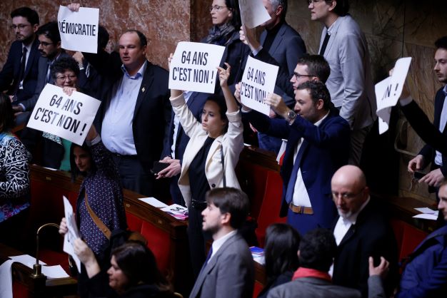 Far-left lawmakers react as they hold papers reading: 