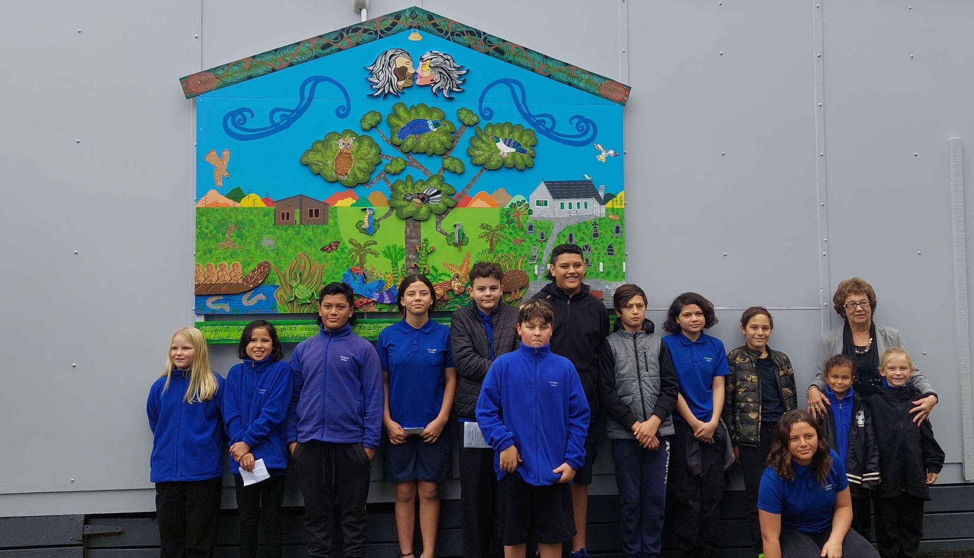 The new Pamapuria School mural with Gloria Seddon (relief teacher/former acting principal) and the students who helped create the mural. Photo / Myjanne Jensen