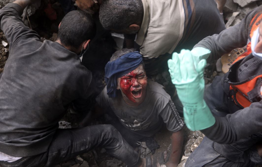 An injured Palestinian boy cries as rescuers try to pull him out of the rubble of a destroyed building following an Israeli airstrike in Bureij refugee camp, Gaza Strip. Photo / AP