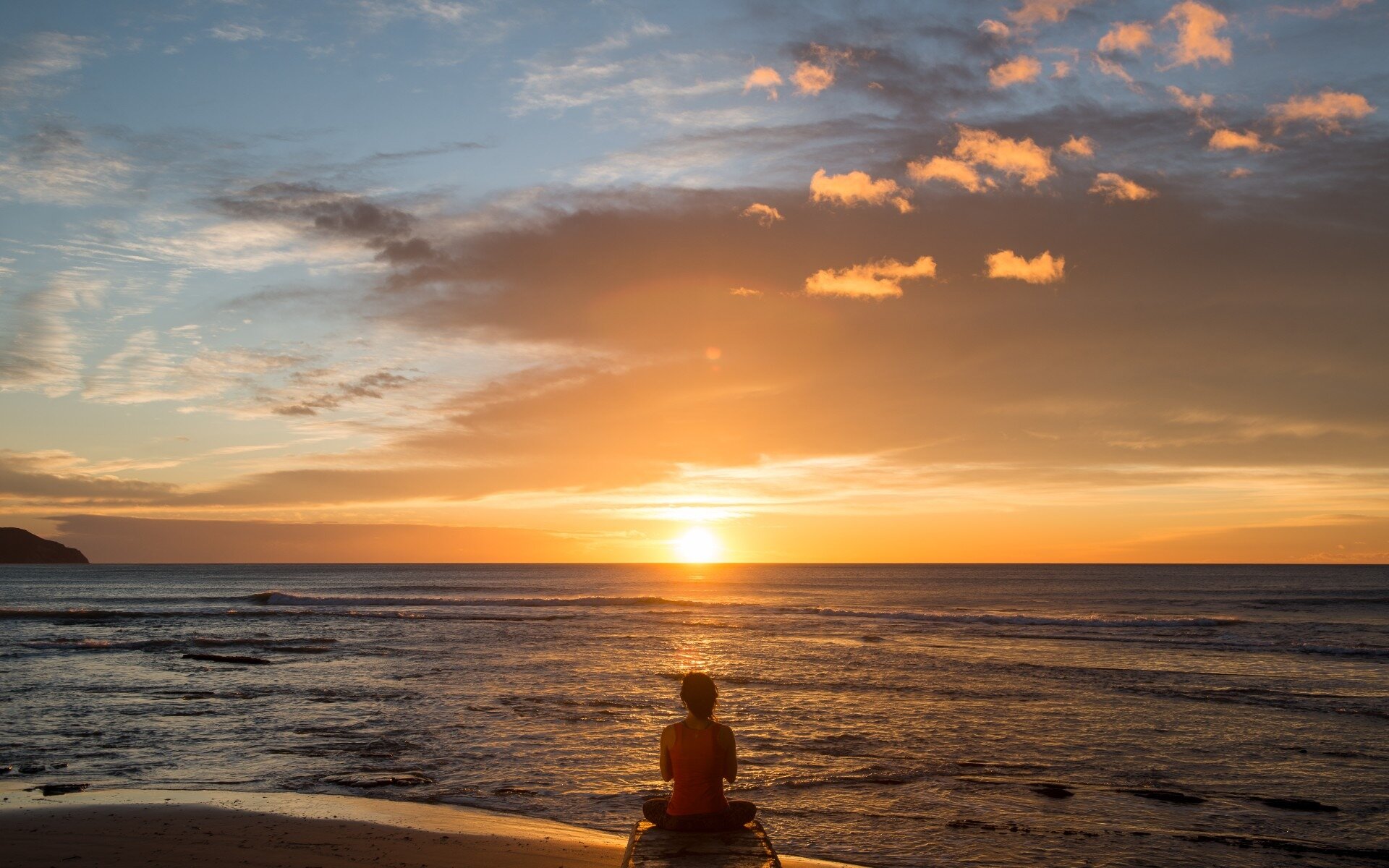 Health coach and meditation guide Becs Erickson practises meditation as the sun rises over Wainui Beach, Gisborne.