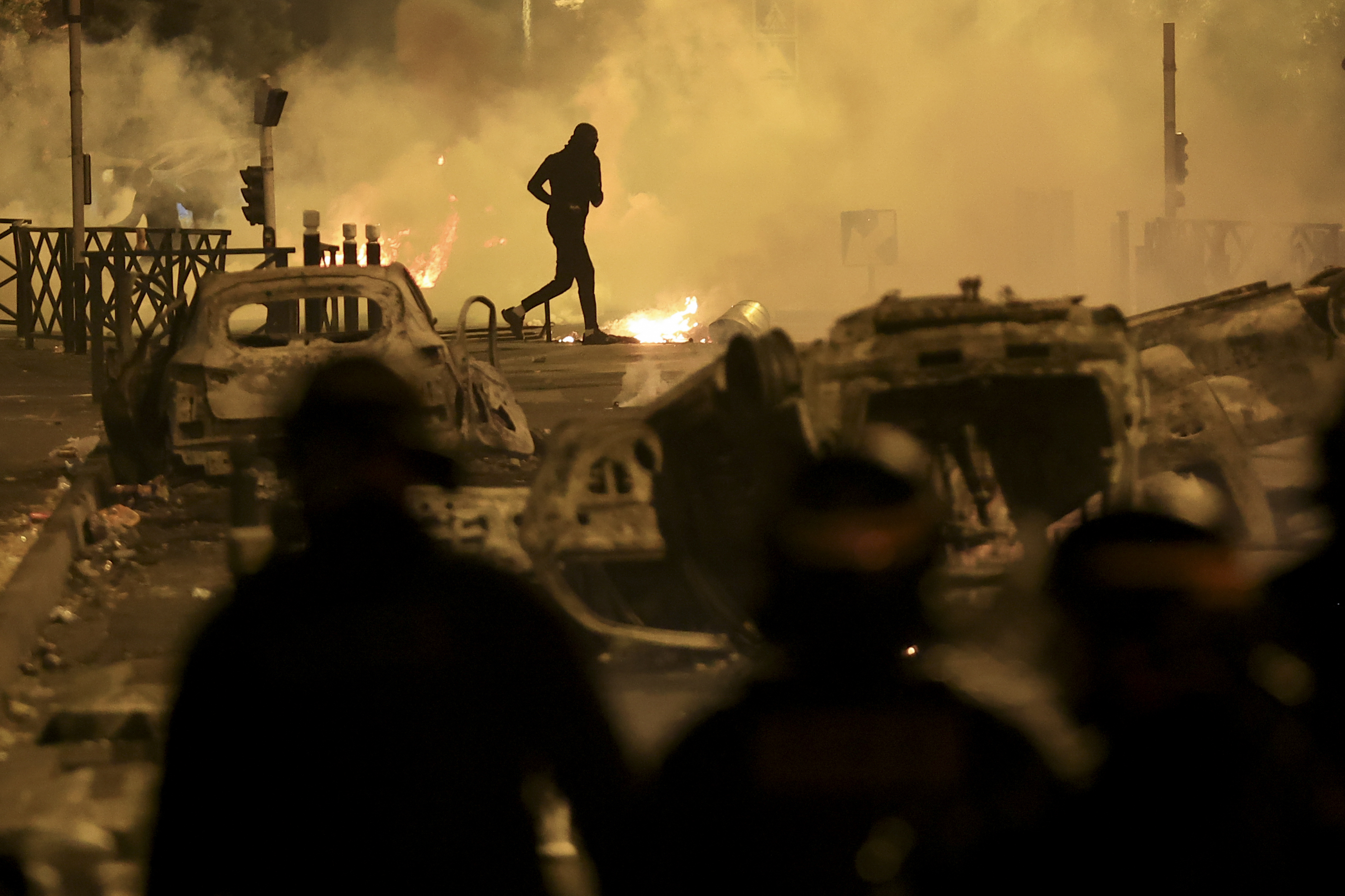 A demonstrator runs on the third night of protests sparked by the fatal police shooting of a 17-year-old driver in the Paris suburb of Nanterre, France. Photo / AP