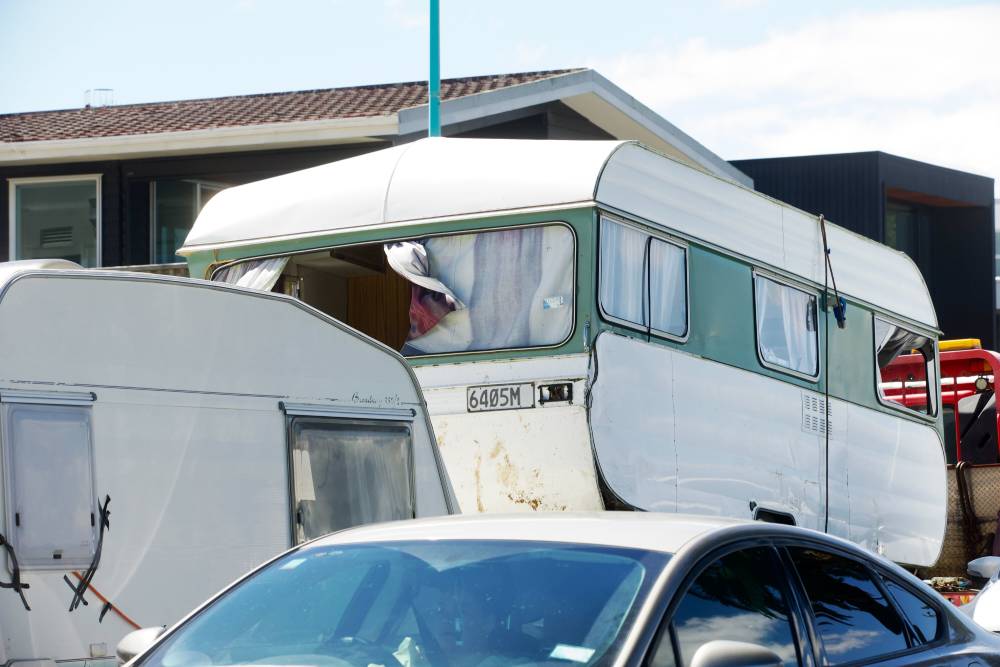A damaged caravan on a tow truck getting removed from the Mount Maunganui Beachside Holiday Park landslide scene. Photo / Jason Dorday