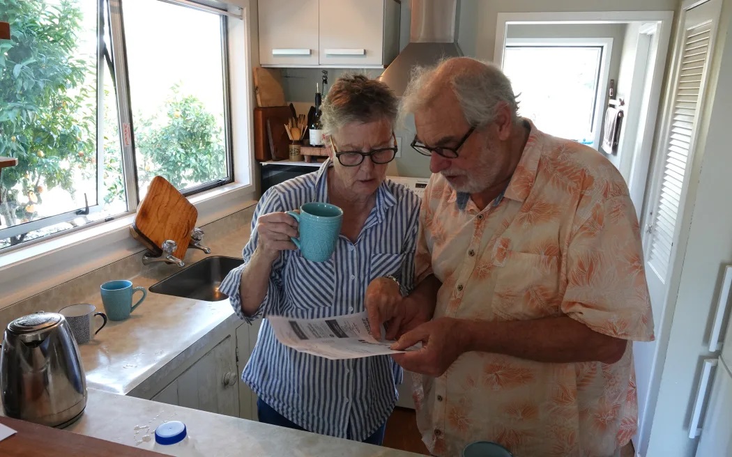 Kerikeri retirees John Logie and Lyn Bellinger, of Kerikeri, study their latest power bill. Photo / RNZ / Peter de Graaf