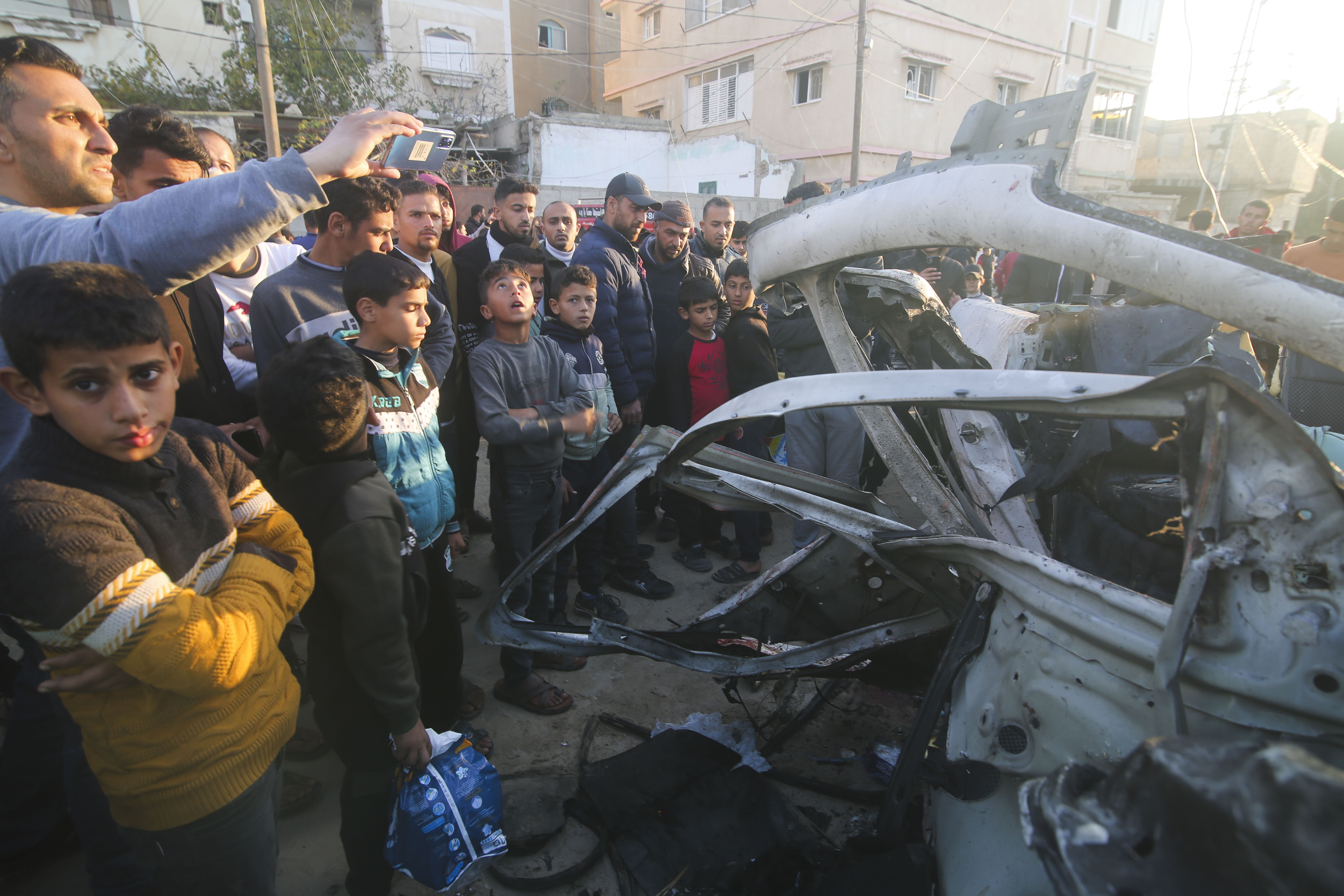 Palestinians gather around a Hamas police vehicle hit by an Israeli airstrike in Rafah, Gaza Strip. Photo / AP