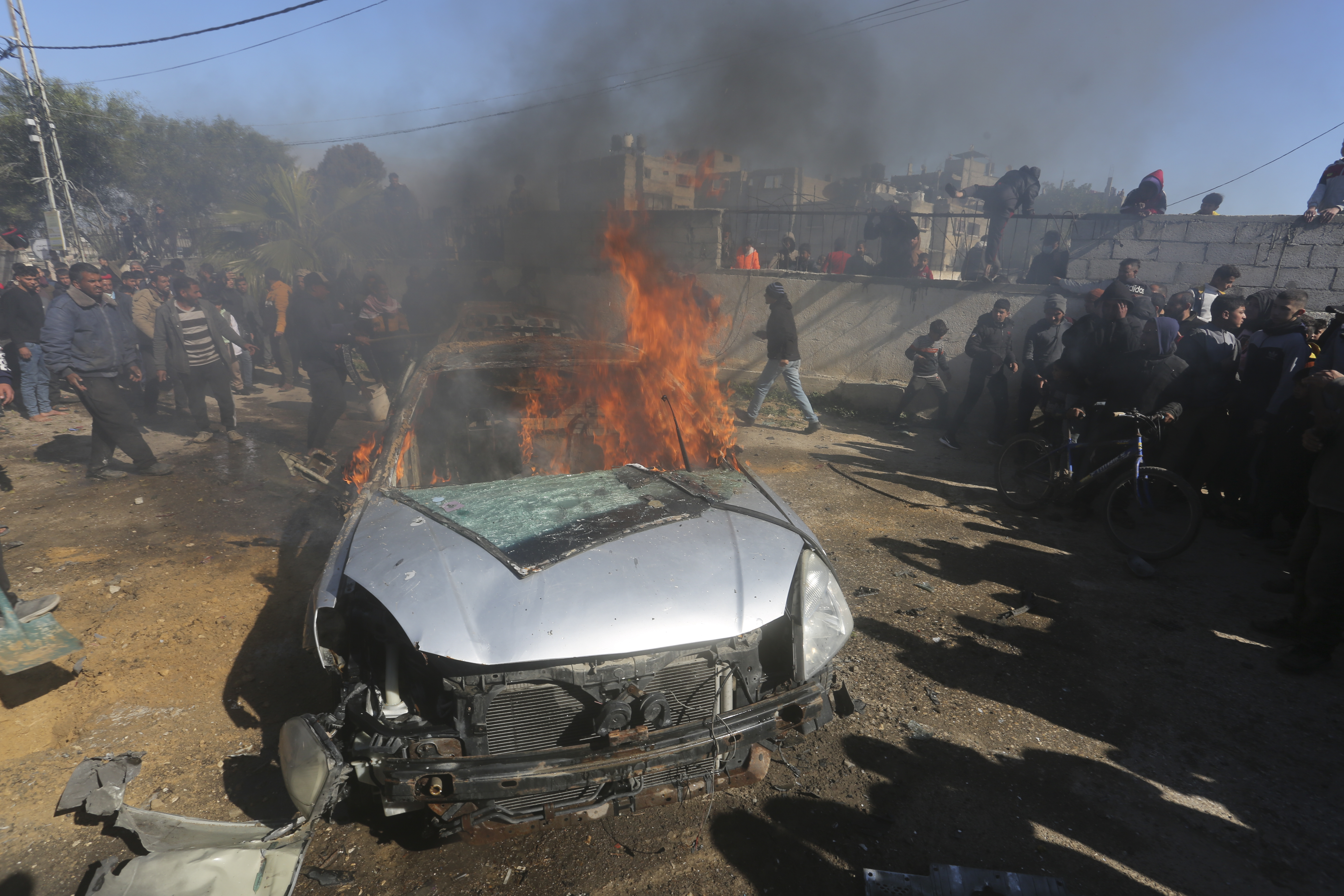 Palestinians watch a car burn after it was hit by an Israeli strike in Rafah, Gaza Strip. Photo / AP