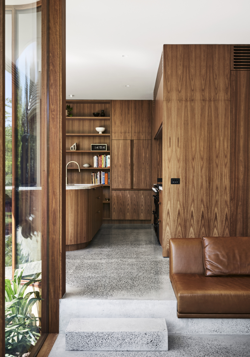 A long, sunken leather lounge is an inviting resting spot that blends seamlessly with the richness of the wall panelling behind it. Photo / Tess Kelly