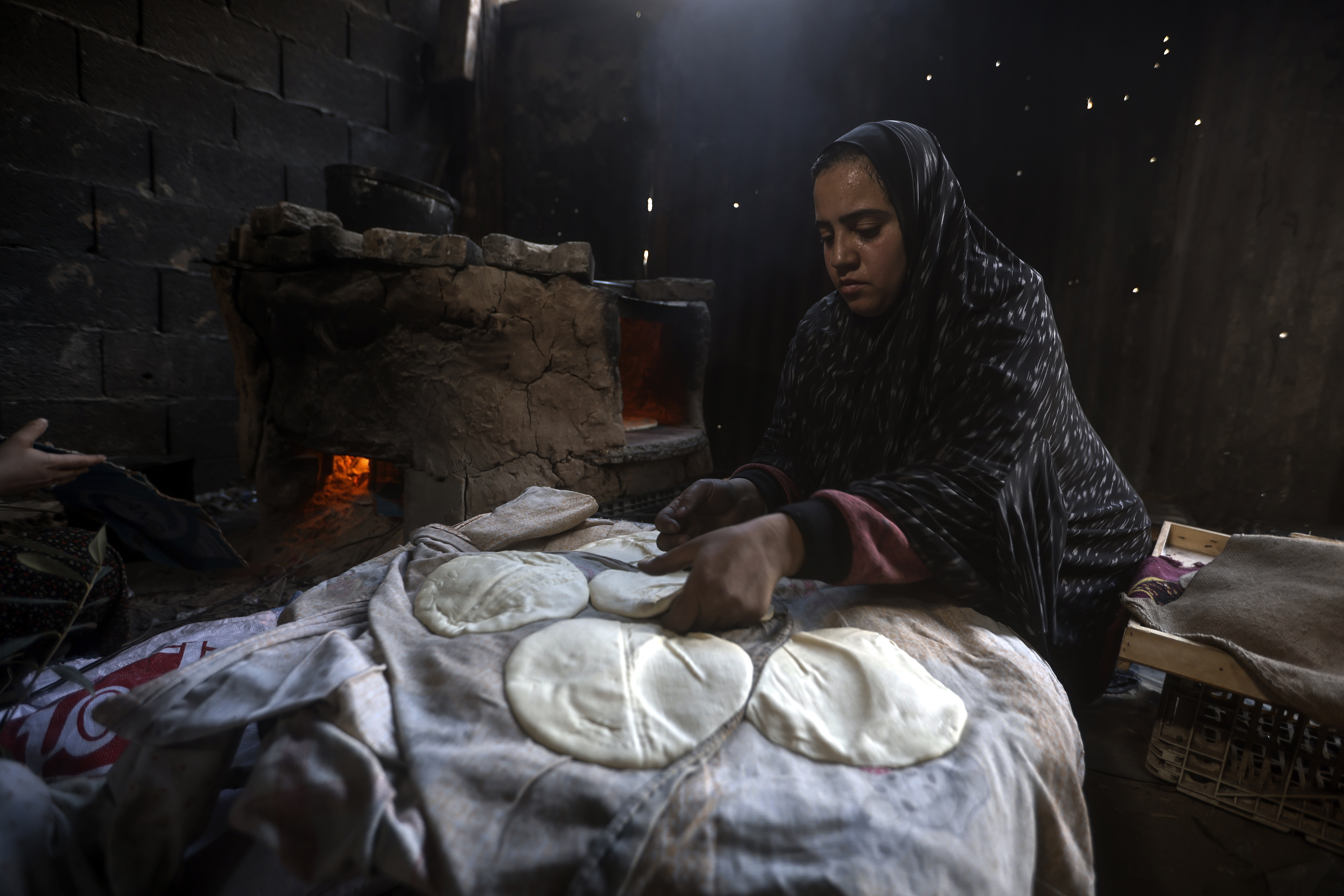 A Palestinian woman displaced by the Israeli ground offensive on the Gaza Strip bakes bread at a makeshift tent camp in Rafah. Photo / AP