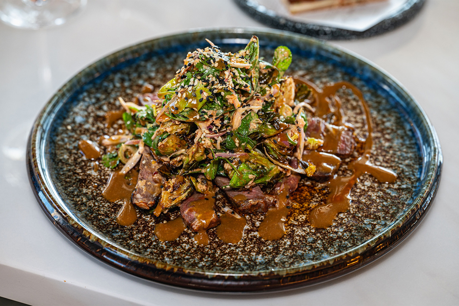 The charred hanger steak, topped with Brussels sprouts and sesame seeds. Photo / Ruby Bloom Photography