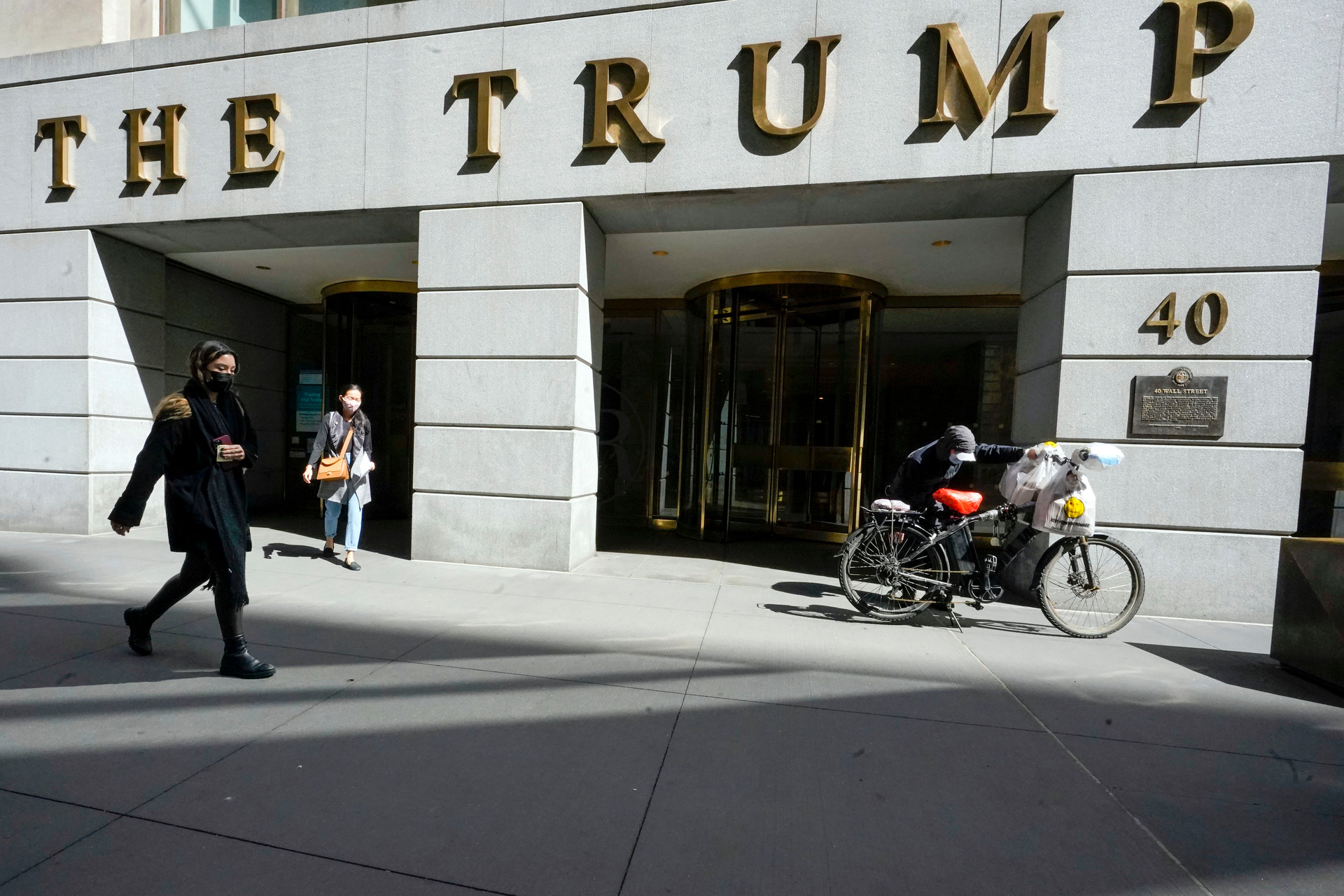 Pedestrians and a food delivery man outside the Trump building on Wall Street, in New York's Financial District. Photo / Mary Altaffer, AP, File