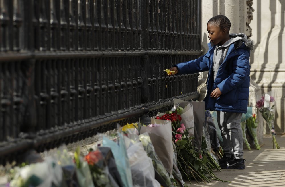 At Buckingham Palace a young boy places a flower on the Palace gate. Photo / AP