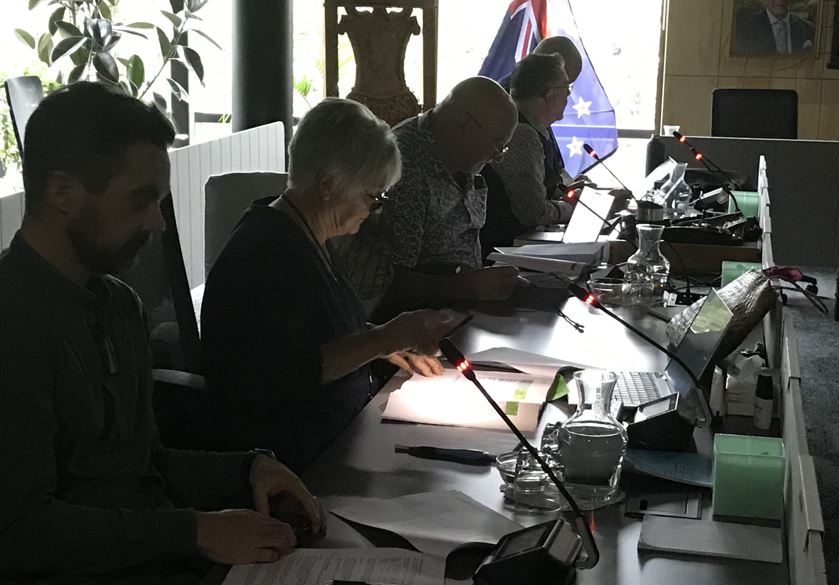 Whangārei District councillor Marie Olsen uses her cell phone for lighting after yesterday morning's power cut plunged Te Iwitahi council chambers into near darkness. Photo / LDR / Susan Botting