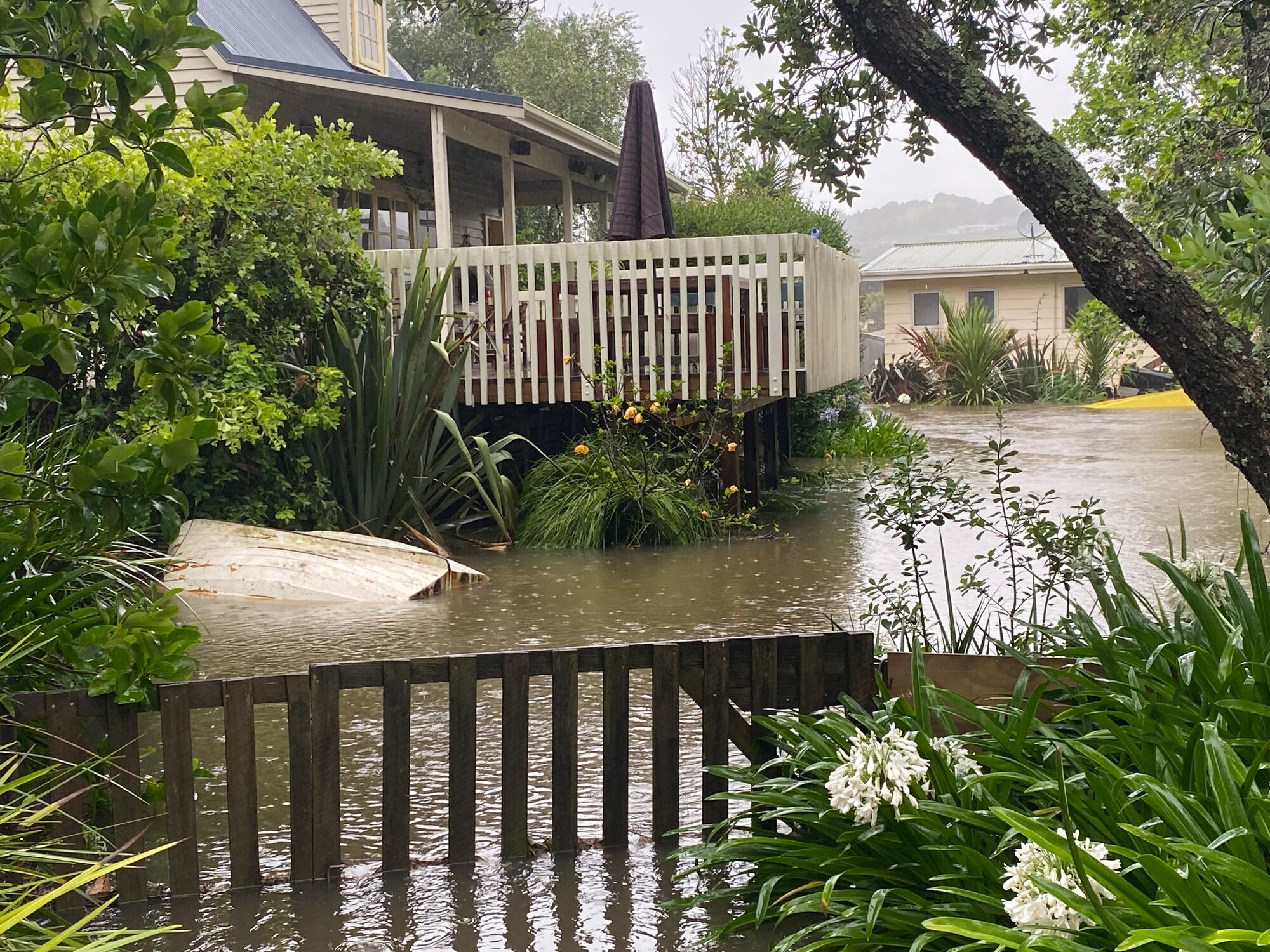 The balcony of a Whangapoua home is threatened by rising waters. Photo / Jane Phare