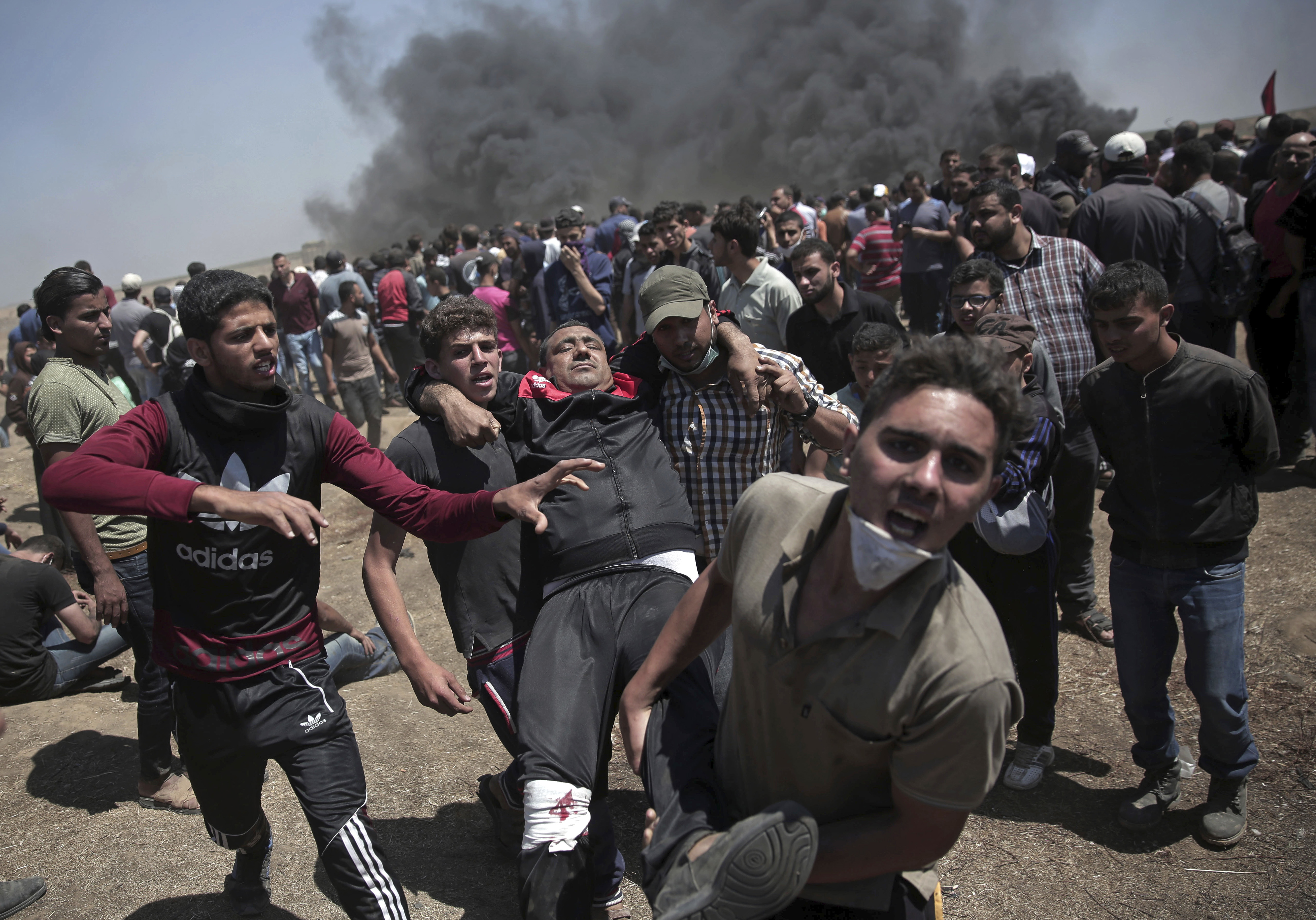 Palestinian protesters carry an injured man who was shot by Israeli troops during a deadly protest at the Gaza Strip's border with Israel. Photo / AP 