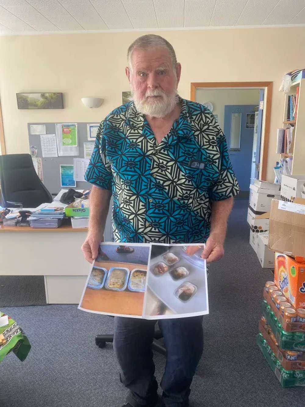 Massey Primary principal Bruce Barnes holding photos of some of the lunches received under the new school lunch programme. Photo / Louise Ternouth, RNZ