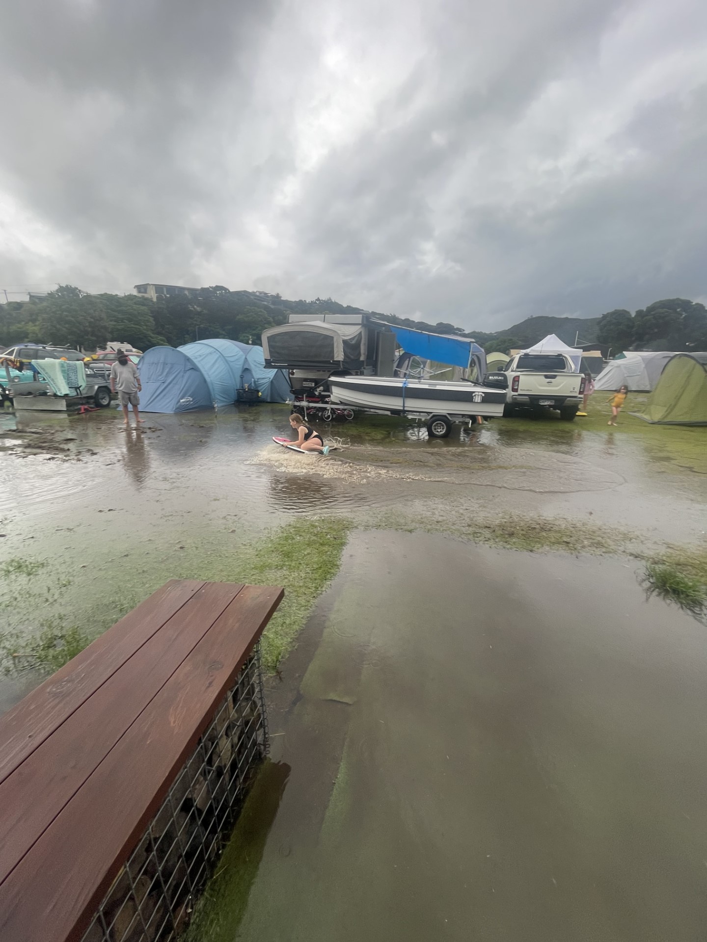 A young girl boogie-boards on floodwater at a campground in Mangawhai on New Year's Eve. Photo / Emma Simpson