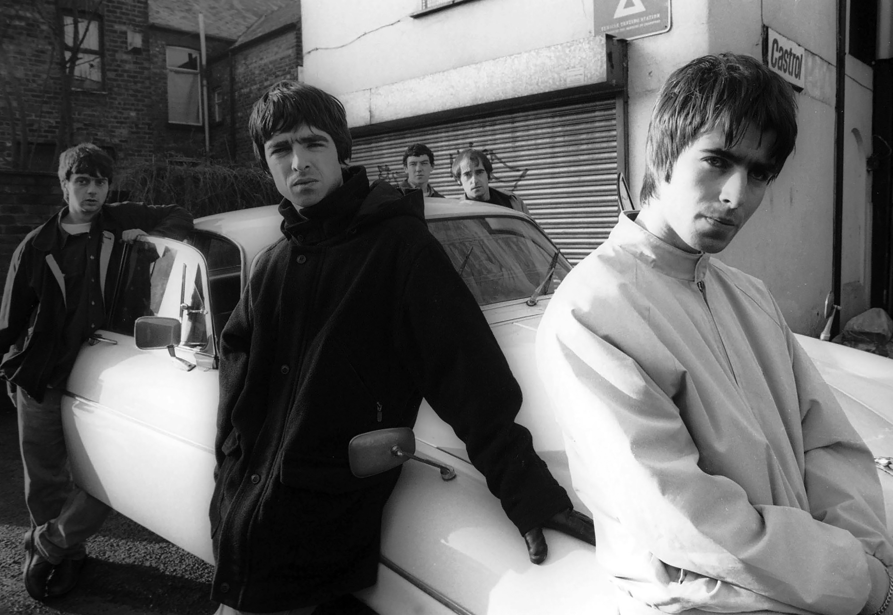Group portrait of British rock band Oasis leaning against a Jaguar XJ6 car in Withington, Manchester, United Kingdom, 30th November 1993. L-R Paul McGuigan, Noel Gallagher, Tony McCarroll, Liam Gallagher, Paul Arthurs (aka Bonehead). (Photo by James Fry/Getty Images)