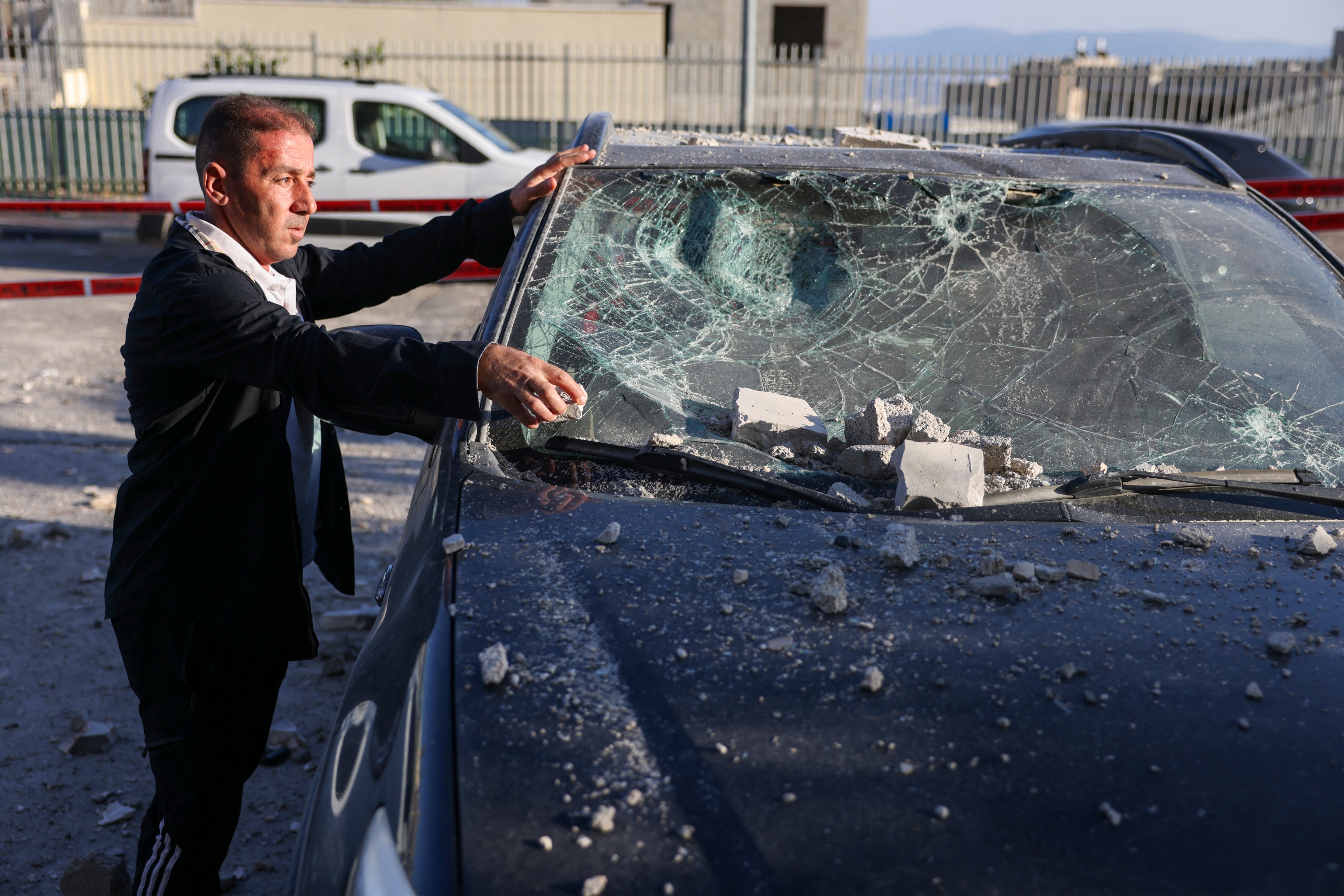 A man clears debris from a car damaged during a rocket attack from southern Lebanon that targeted the northern Arab-Israeli village of Deir al-Asad yesterday. Photo / AFP