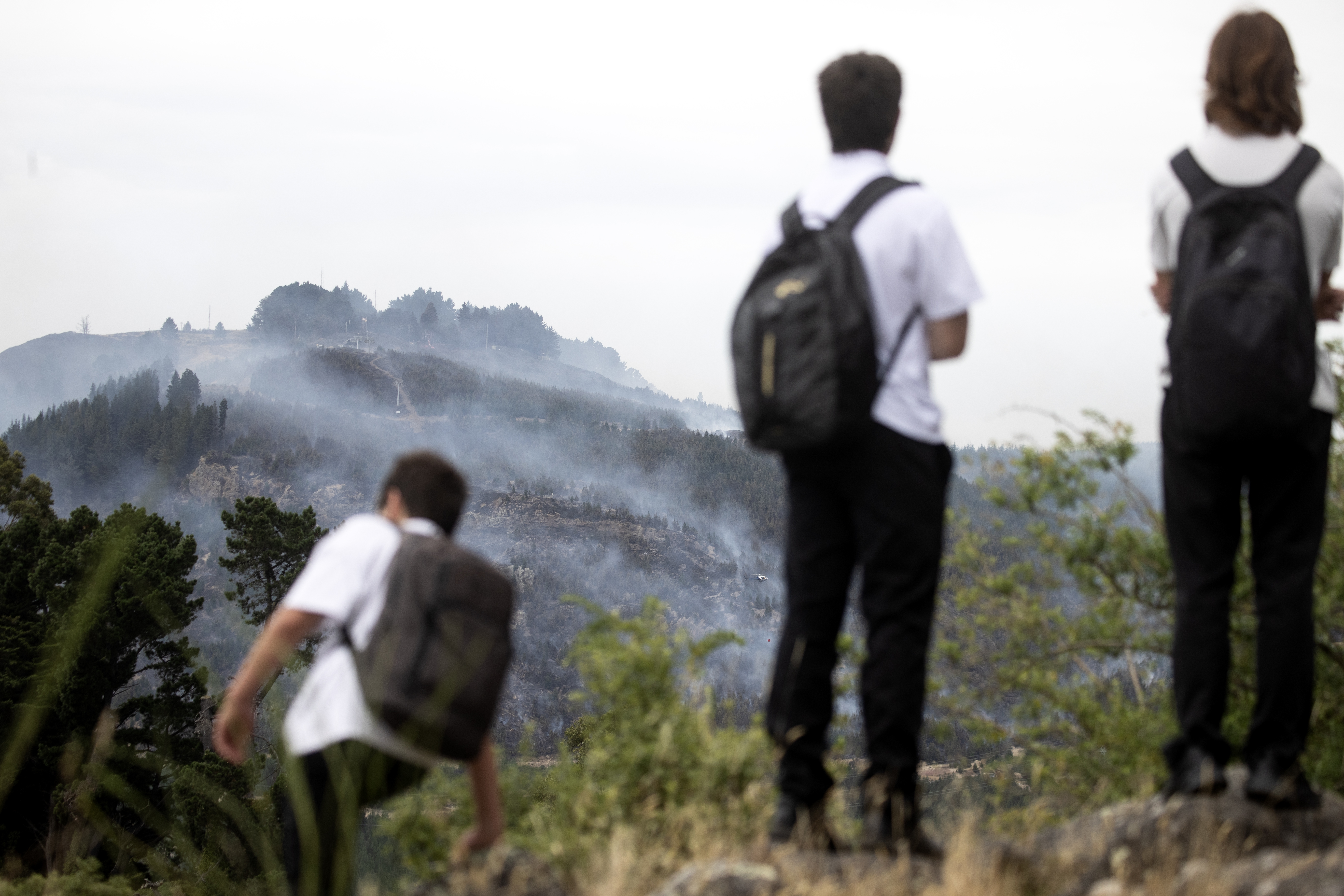 People watch on as the fire smoulders. Photo / George Heard