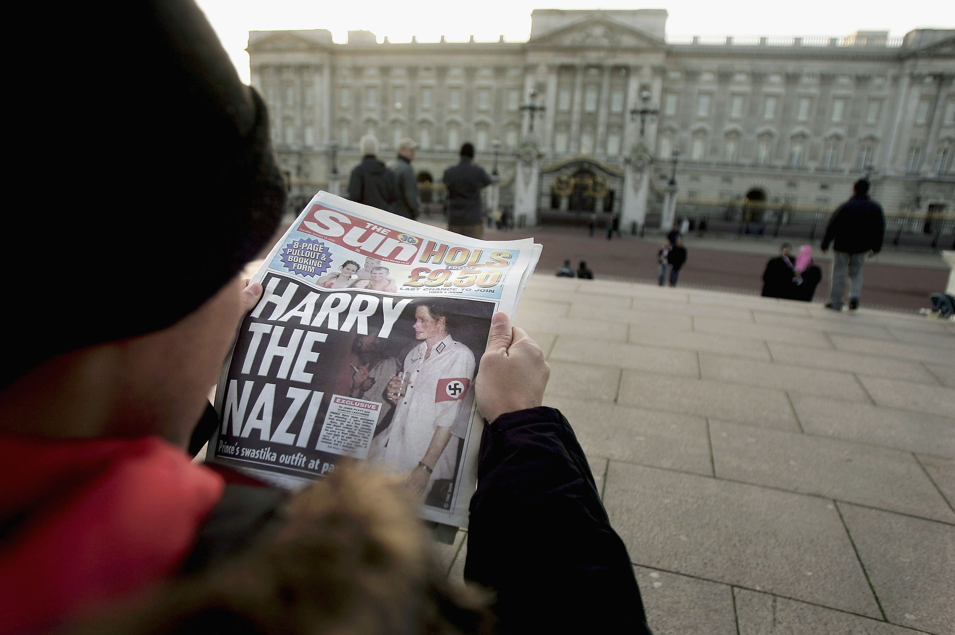 A man reading a copy of The Sun newspaper in front of Buckingham Palace in London on January 13, 2005, after Prince Harry made the headlines on news he arrived at a friend's birthday party dressed in a Nazi outfit. The Prince, who has been fiercely criticised for his actions, apologised for his choice of costume.  Photo / Getty Images