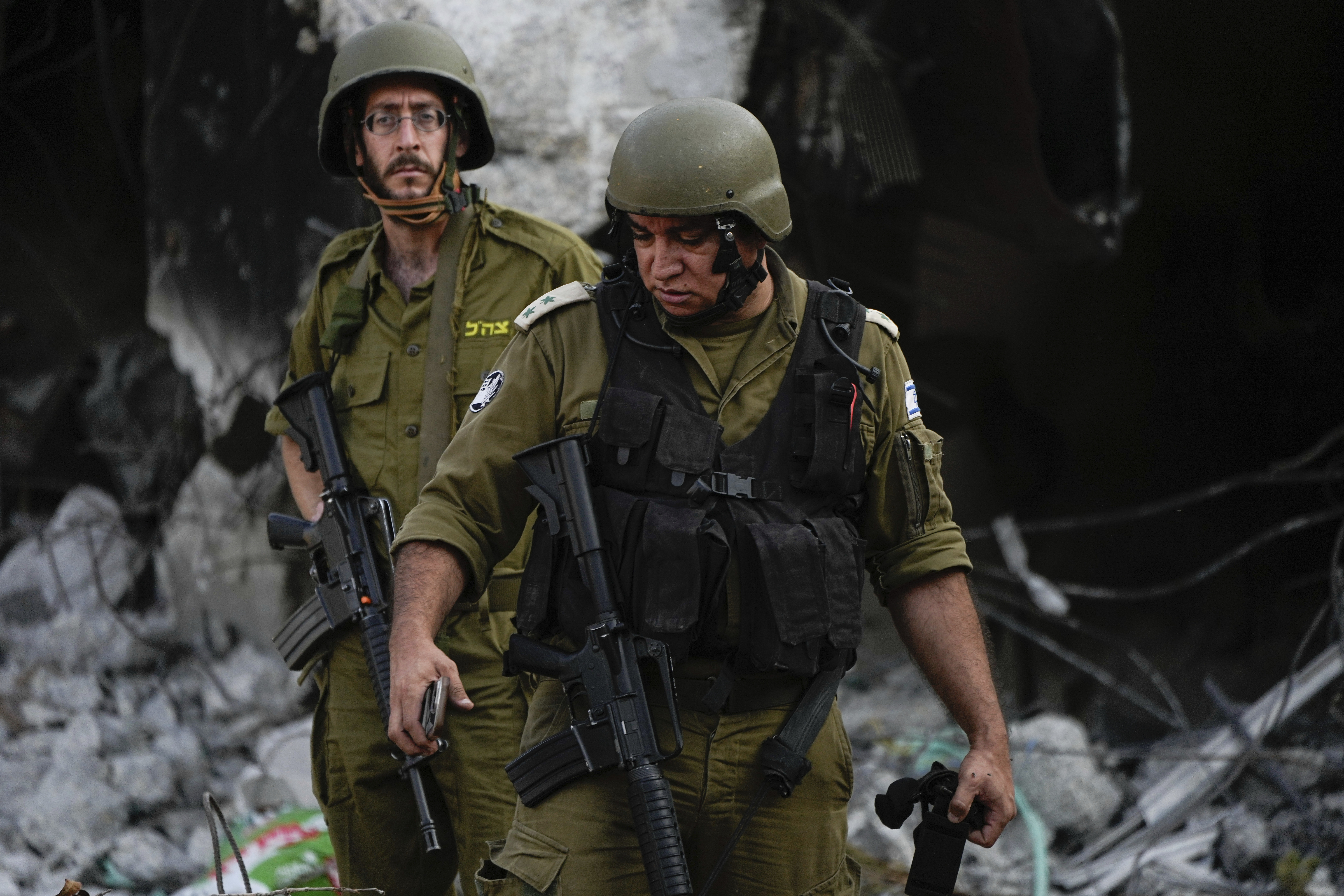 Israeli soldiers walk past houses destroyed by Hamas militants in Kibbutz Be'eri, Israel. Photo / AP