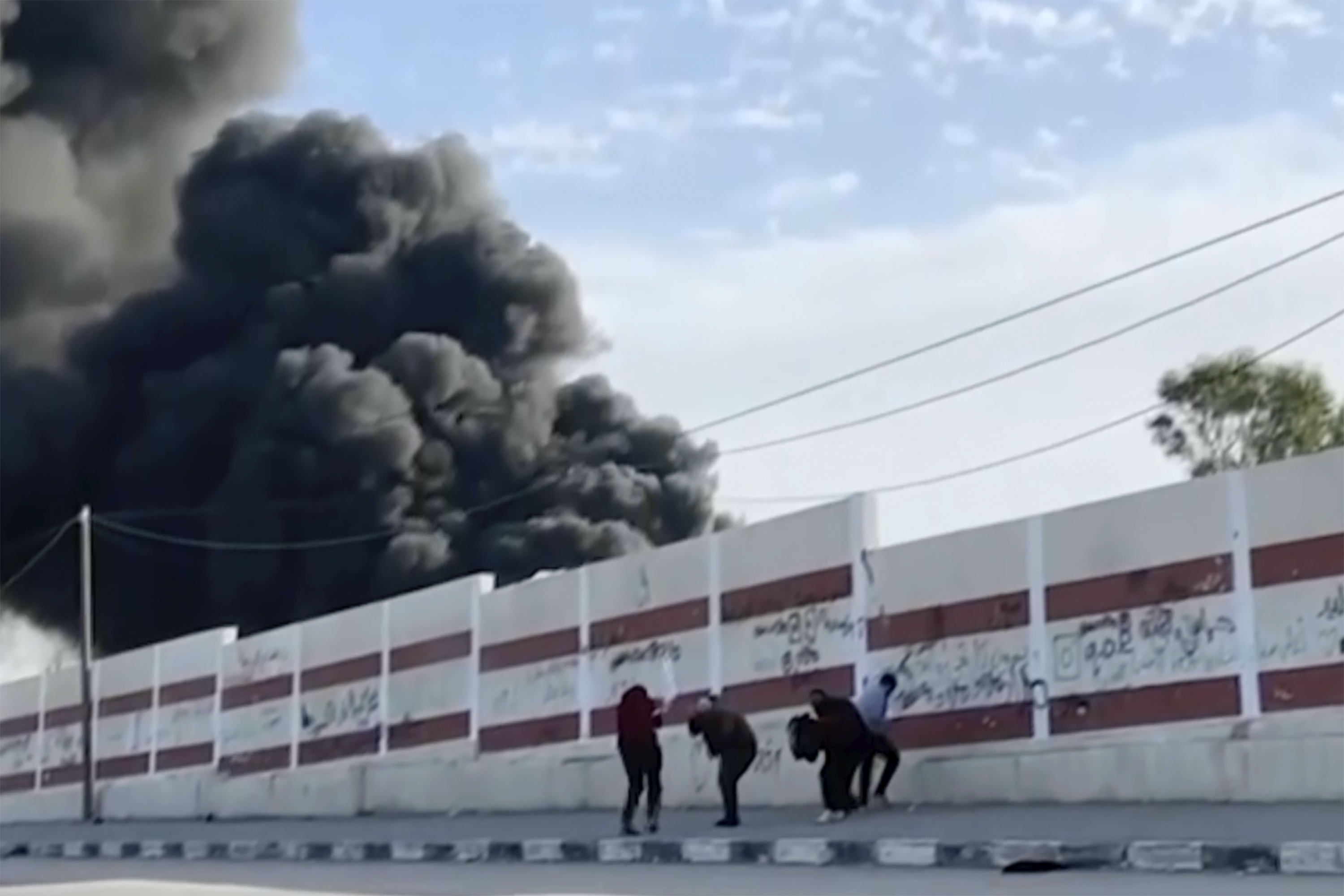 This image made from ITV News video shows a group of five men trying to take cover while walking down a street west of the southern city of Khan Younis in Gaza. Earlier, they could be seen holding their hands in the air, and one waved a white flag. Israel's military has announced it will review the fatal shooting of one of the men. Photo / AP