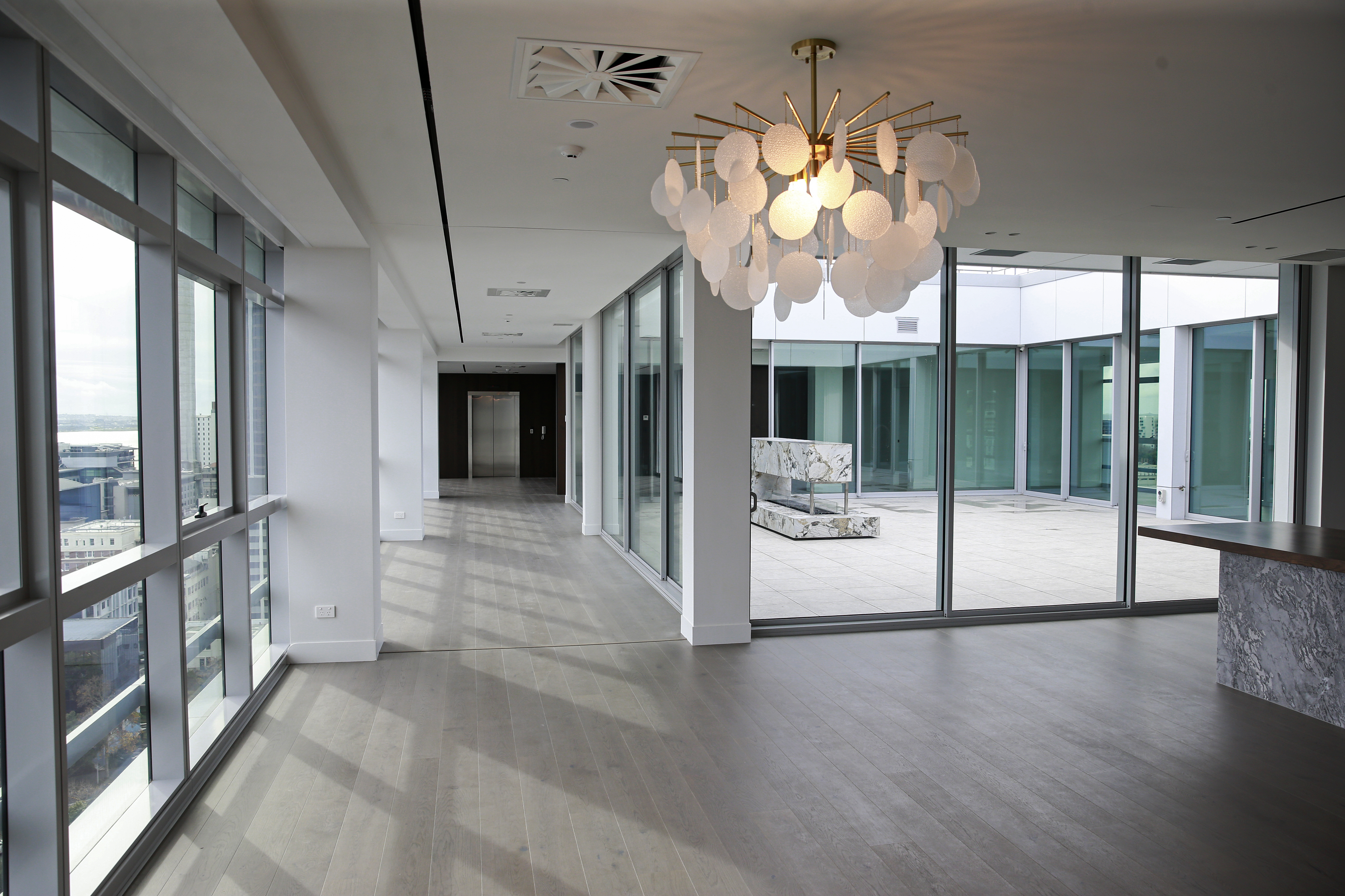 Entrance lobby, outdoor courtyard and kitchen area of the luxury level 18 apartment in The CAB. Photo / Alex Burton