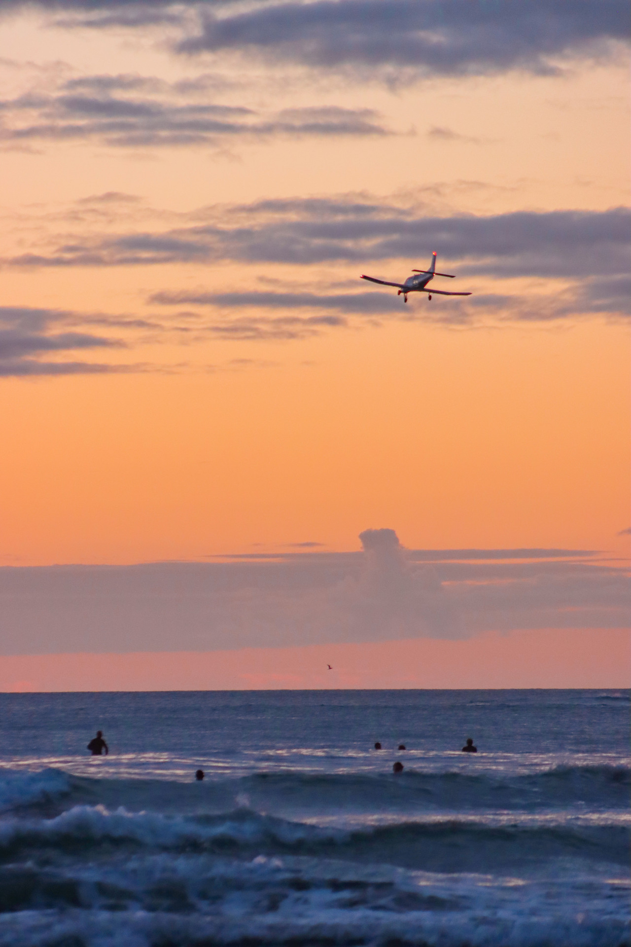 A skydiving plane circles over the ocean off Muriwai Beach where Sarah-Jane Bayram died after colliding with another skydiver during a formation jump in March 2022.