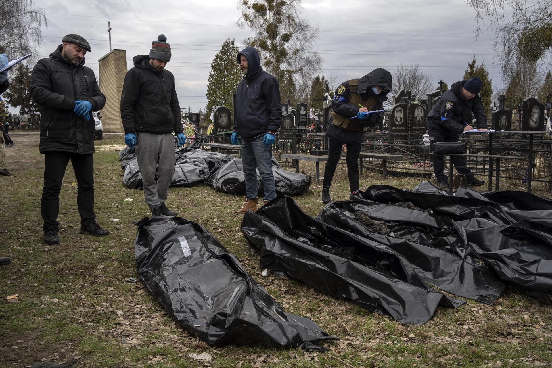 Vladyslav Minchenko, left, with policemen collect information next to corpses of civilians killed in Bucha, before the corpses are transported to the morgue, on the outskirts of Kyiv. Photo / AP
