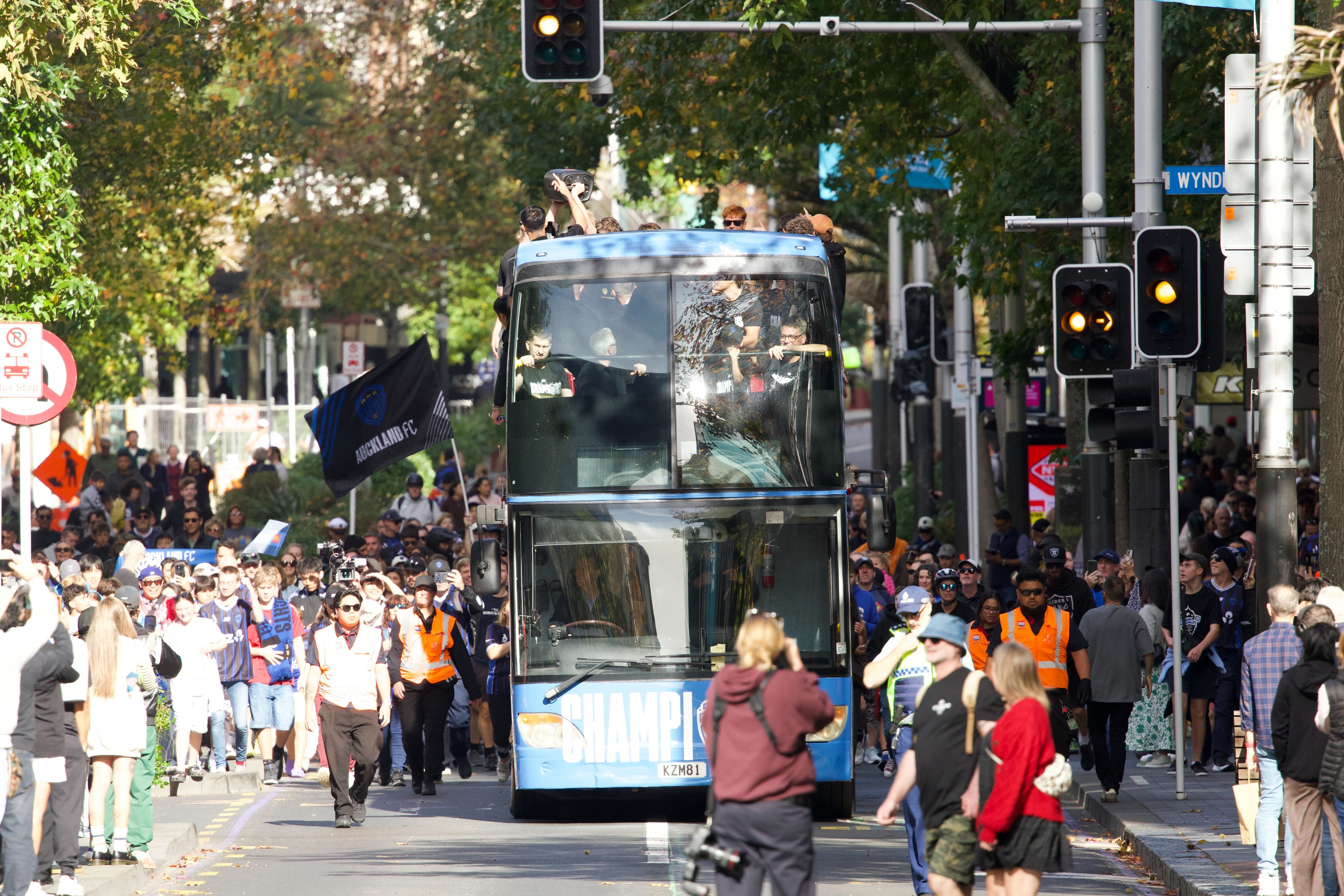 Auckland FC's bus winds its way down Queen St as thousands turn out for the victory parade. Photo / Jason Dorday