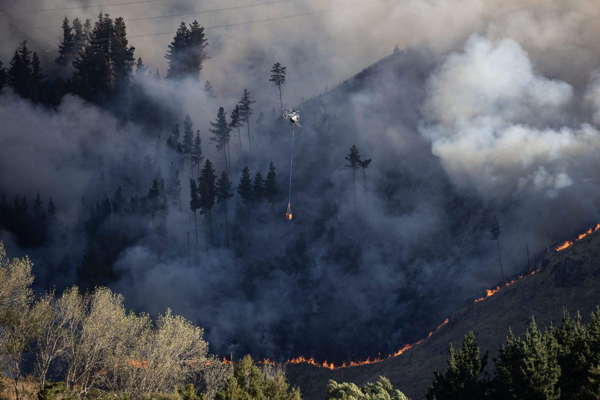 Firefighters battling a fire on Christchurch's Port Hills. A dozen helicopters worked to stop the blaze last night. Photo / George Heard