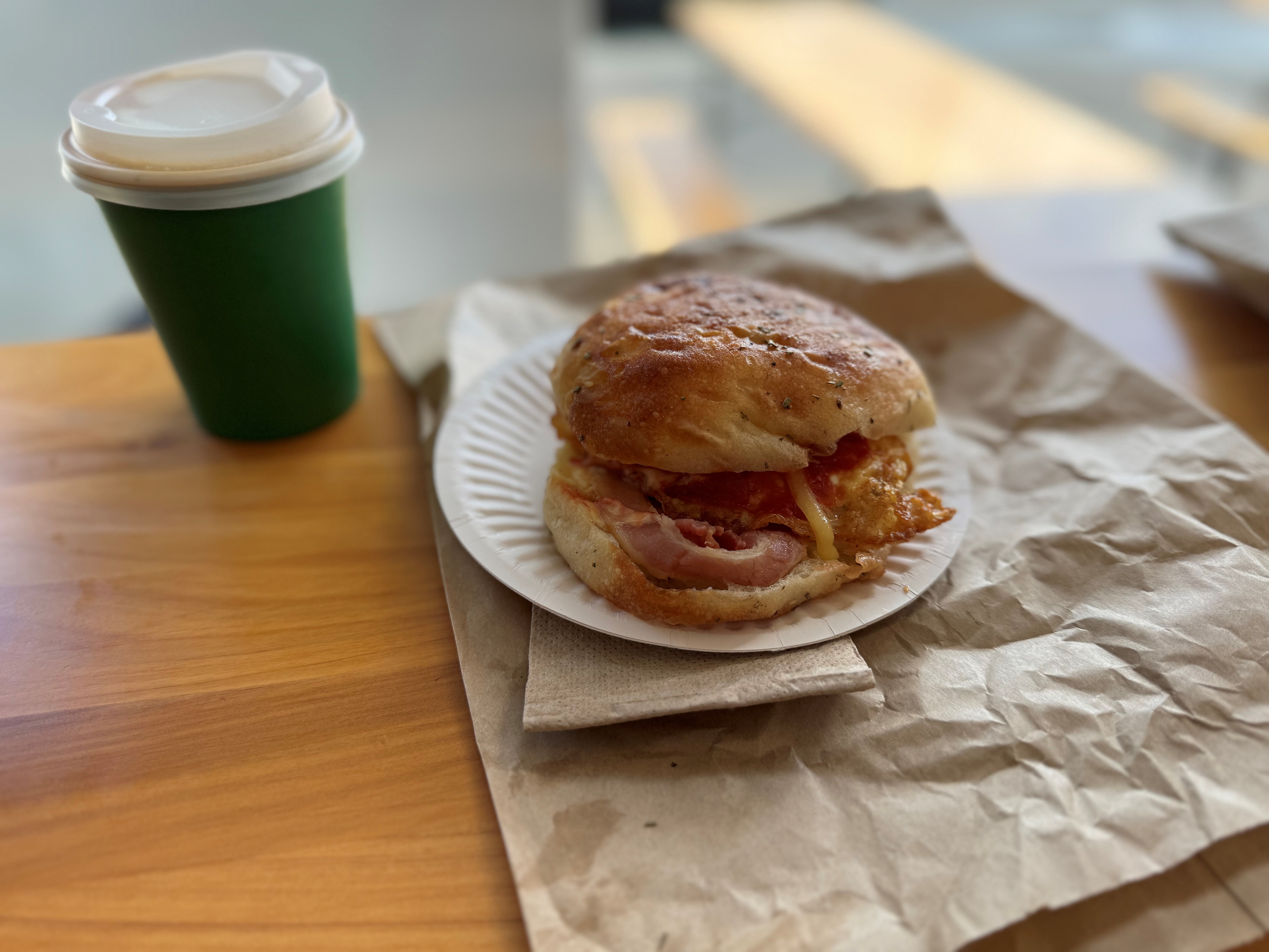 Annabelle White revels in the perfectly cooked egg and bacon sandwich with homemade tomato relish on sesame pide rolls from Rollers Bakery in Northcote, Auckland.