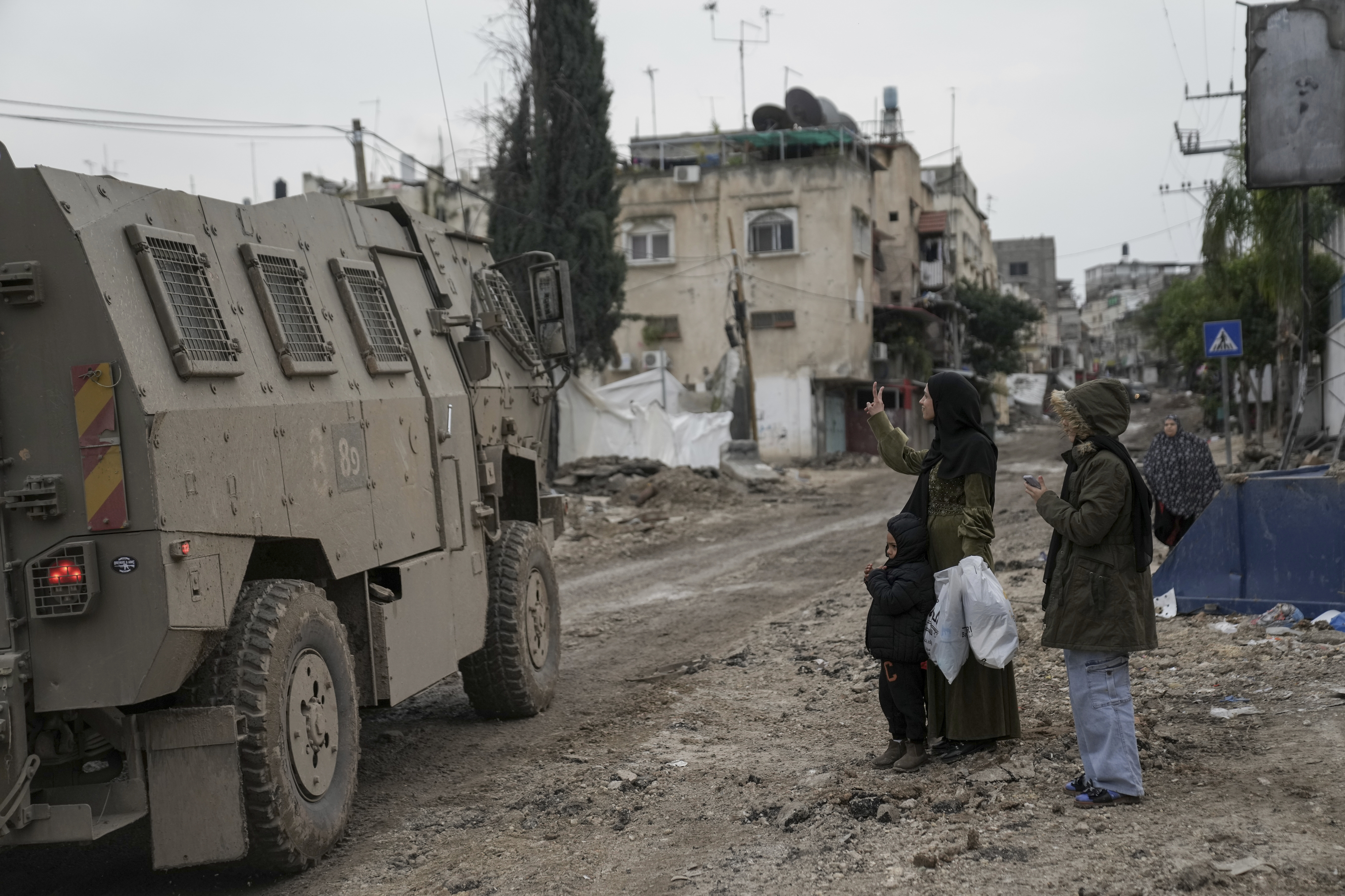 A Palestinian woman flashes a V-sign towards Israeli troops during an army raid in the Tulkarem refugee camp, West Bank. Photo / AP
