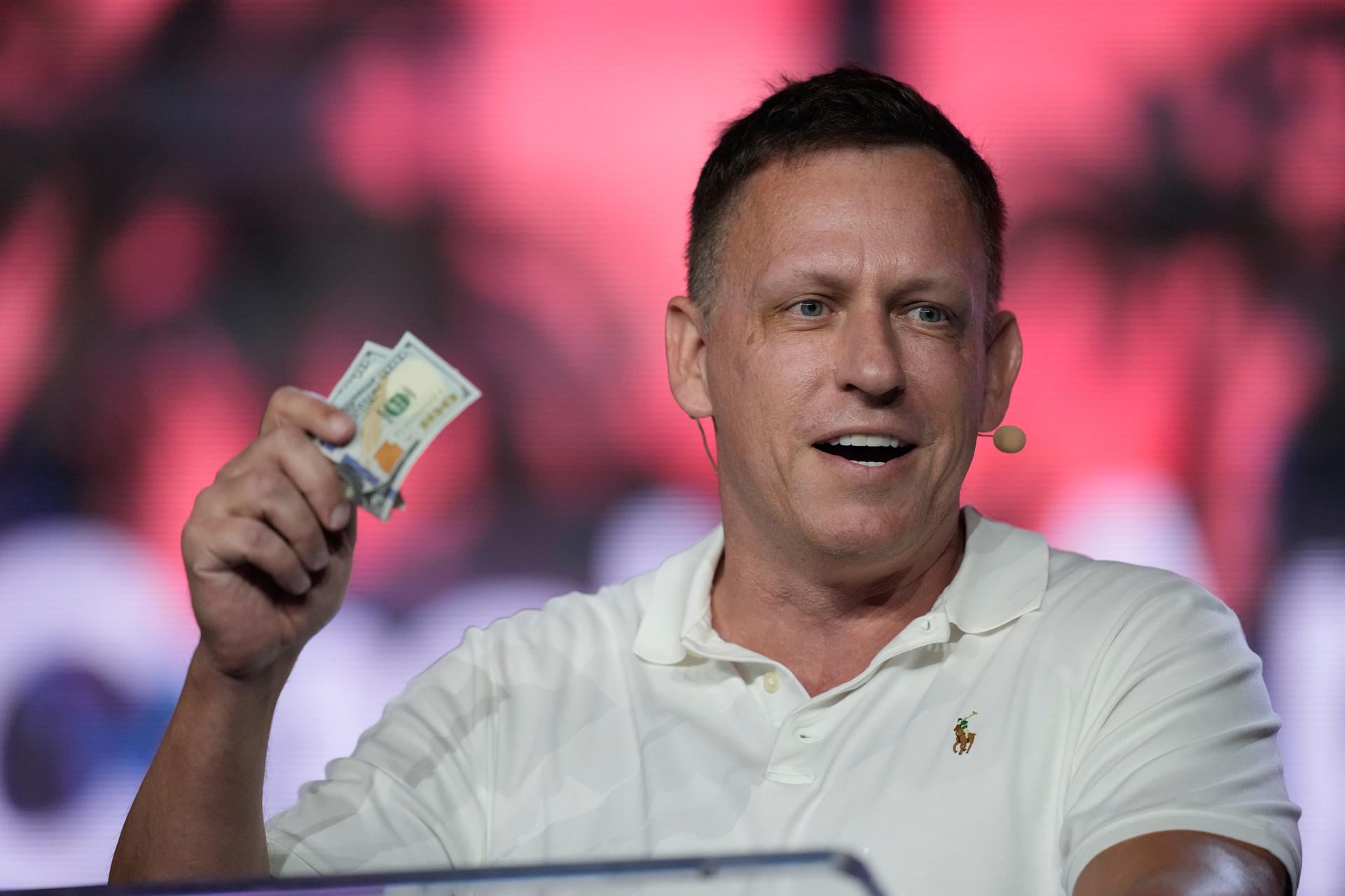 Peter Thiel offering dollar bills to attendees during an address at a Bitcoin Conference on April 7, 2022, in Miami Beach. Photo / Rebecca Blackwell, AP