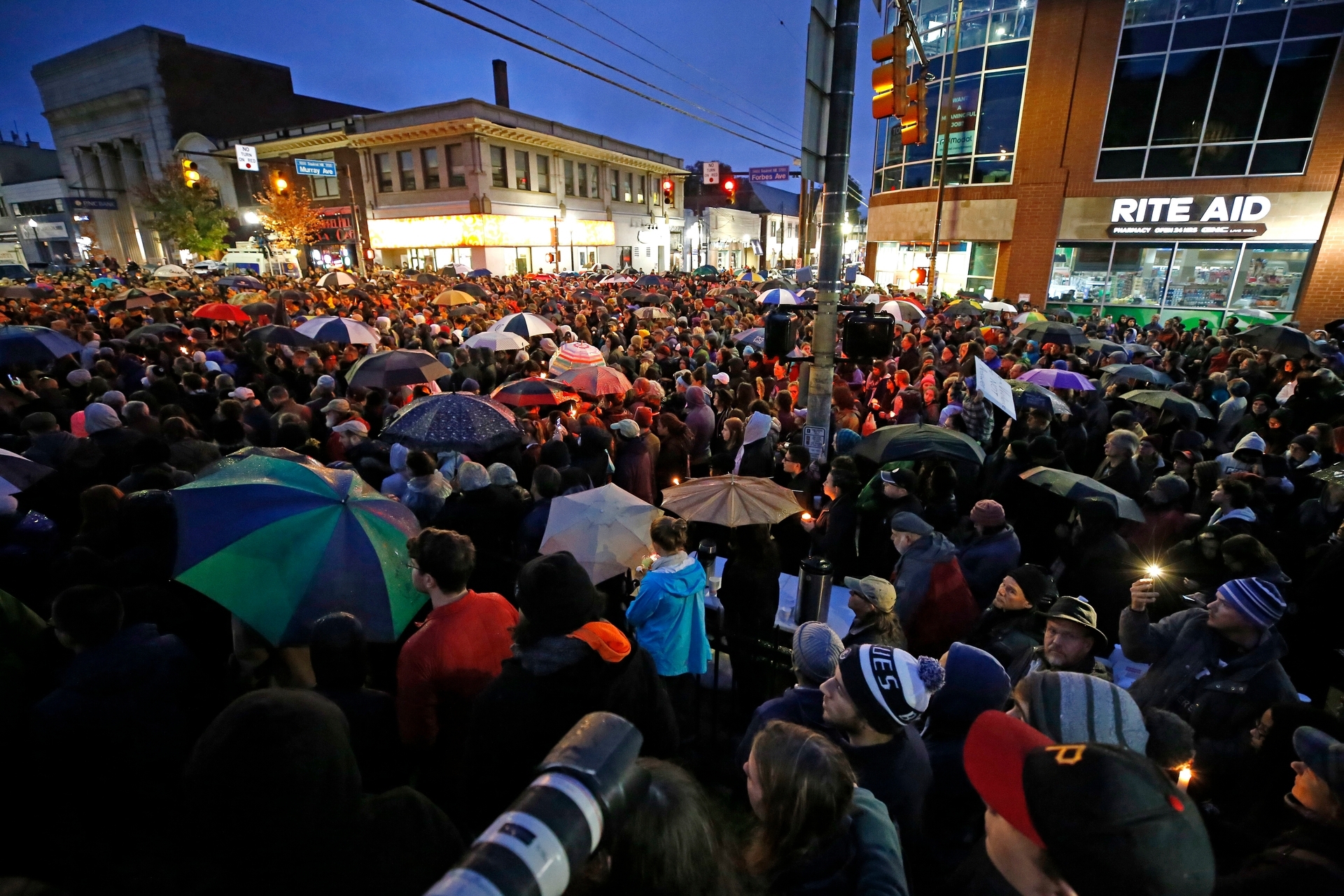 A crowd gathers at Squirrel Hill, Pittsburgh, during a vigil. A webpage from Gab, left, with a posting by suspect Robert Bowers. Photo / AP