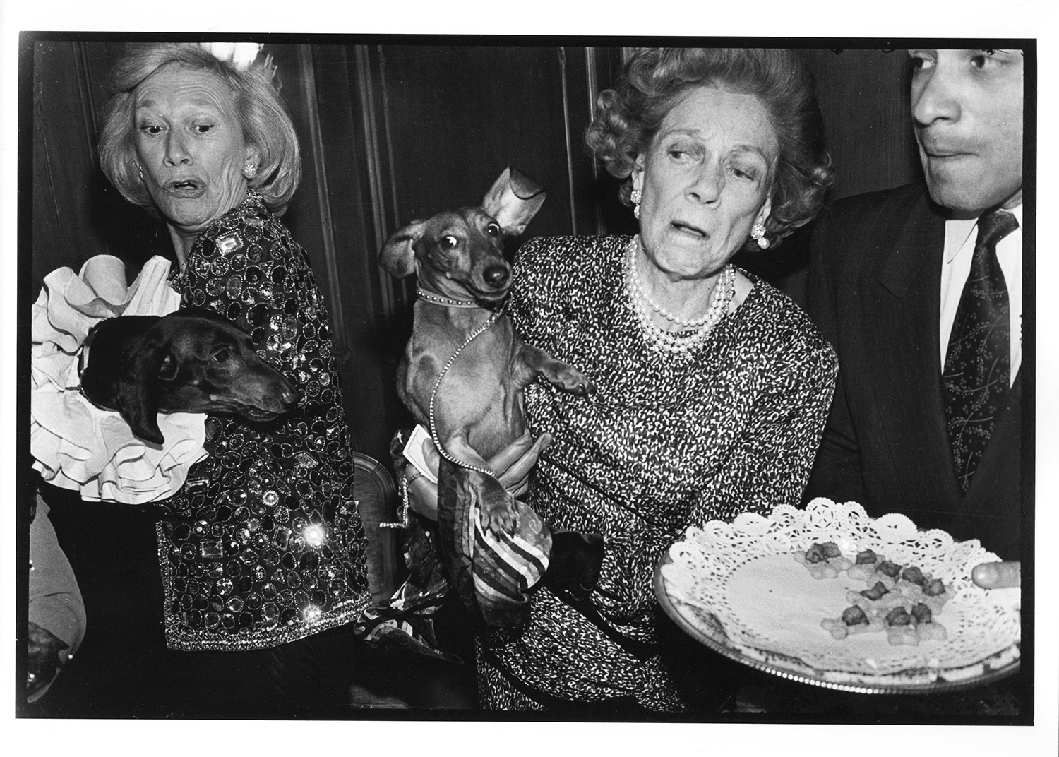 Iris Love and Brooke Astor restrain dachshunds lunging for the canapés at a dachshund party at Barbetta in February 1990. Photo / Dafydd Jones via The New York Times