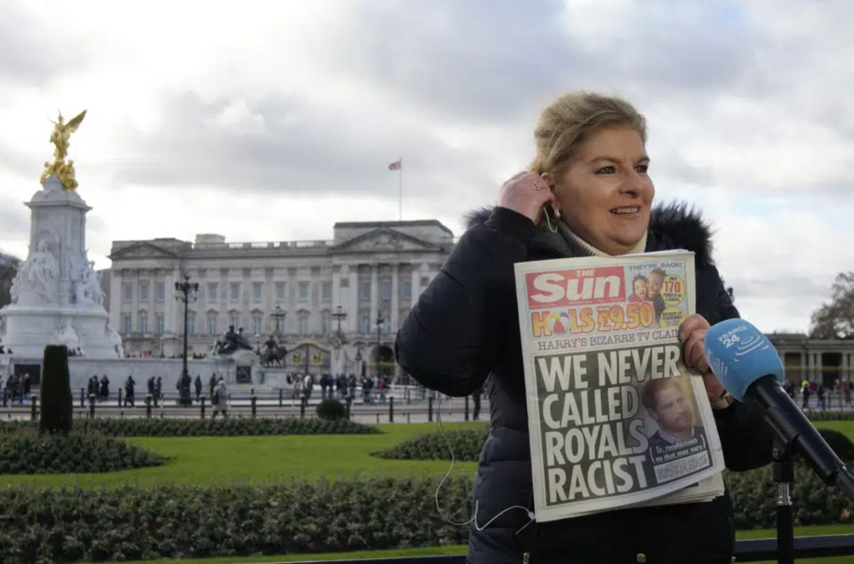 A journalist holds up a copy of a UK newspaper as she reports outside Buckingham Palace. Photo / AP