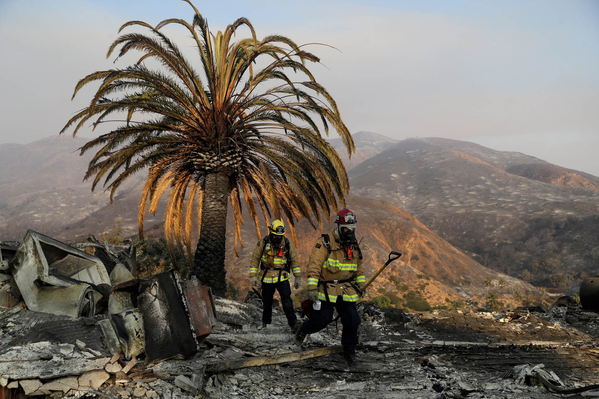 Firefighters Jason Toole, right, and Brent McGill with the Santa Barbara Fire Dept. walk among the ashes of a wildfire-ravaged home. Photo / AP