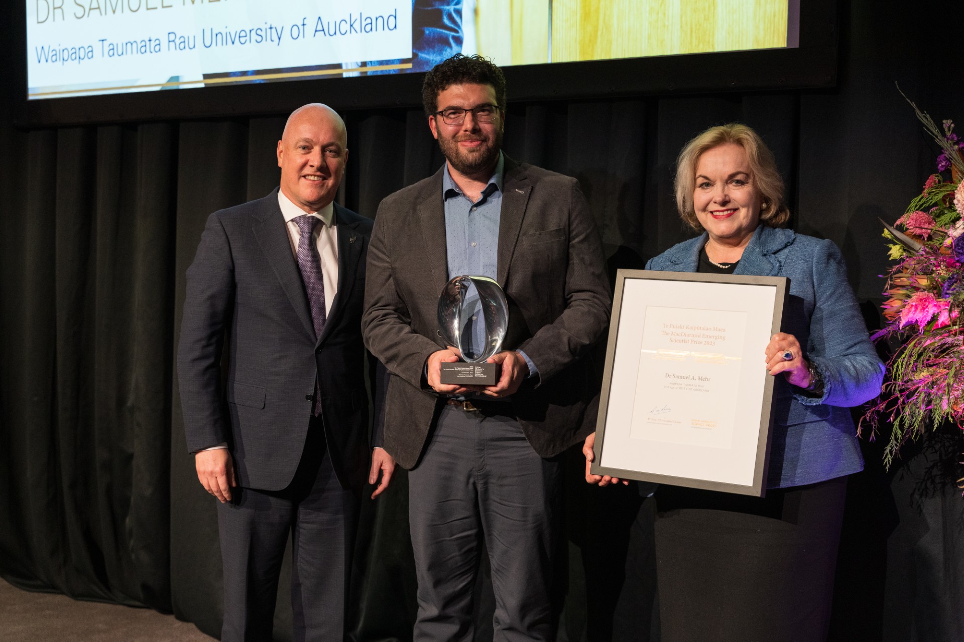University of Auckland cognitive scientist Dr Samuel Mehr (centre) was this year presented the Prime Minister's MacDiarmid Emerging Scientist Prize by Prime Minister Christopher Luxon and Science, Innovation and Technology Minister Judith Collins. Photo / Rebecca McMillan Photography