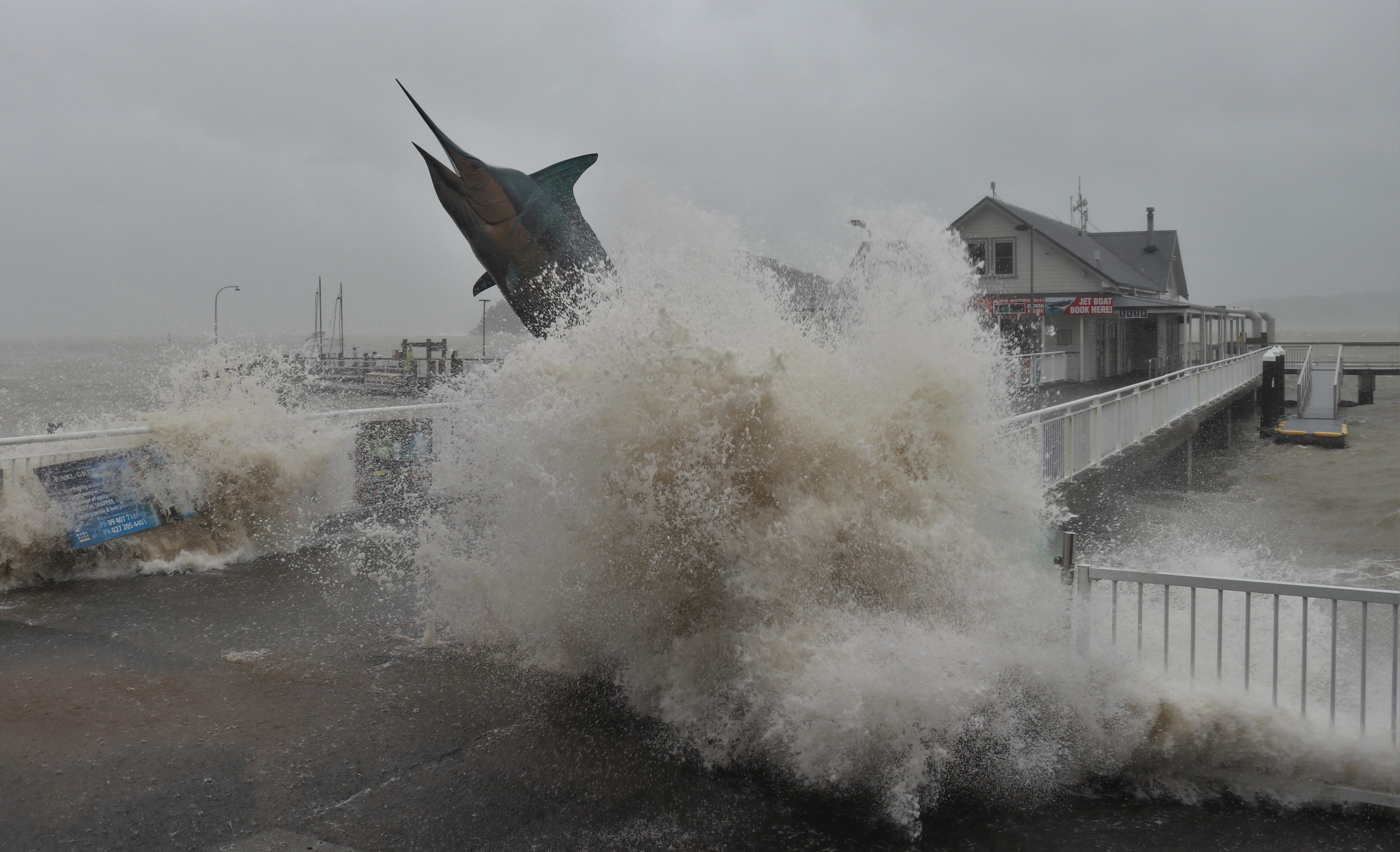 Waves crash over Paihia wharf’s marlin statue, amid massive swells generated by February's ex-tropical cyclone Gabrielle. Photo / Peter de Graaf