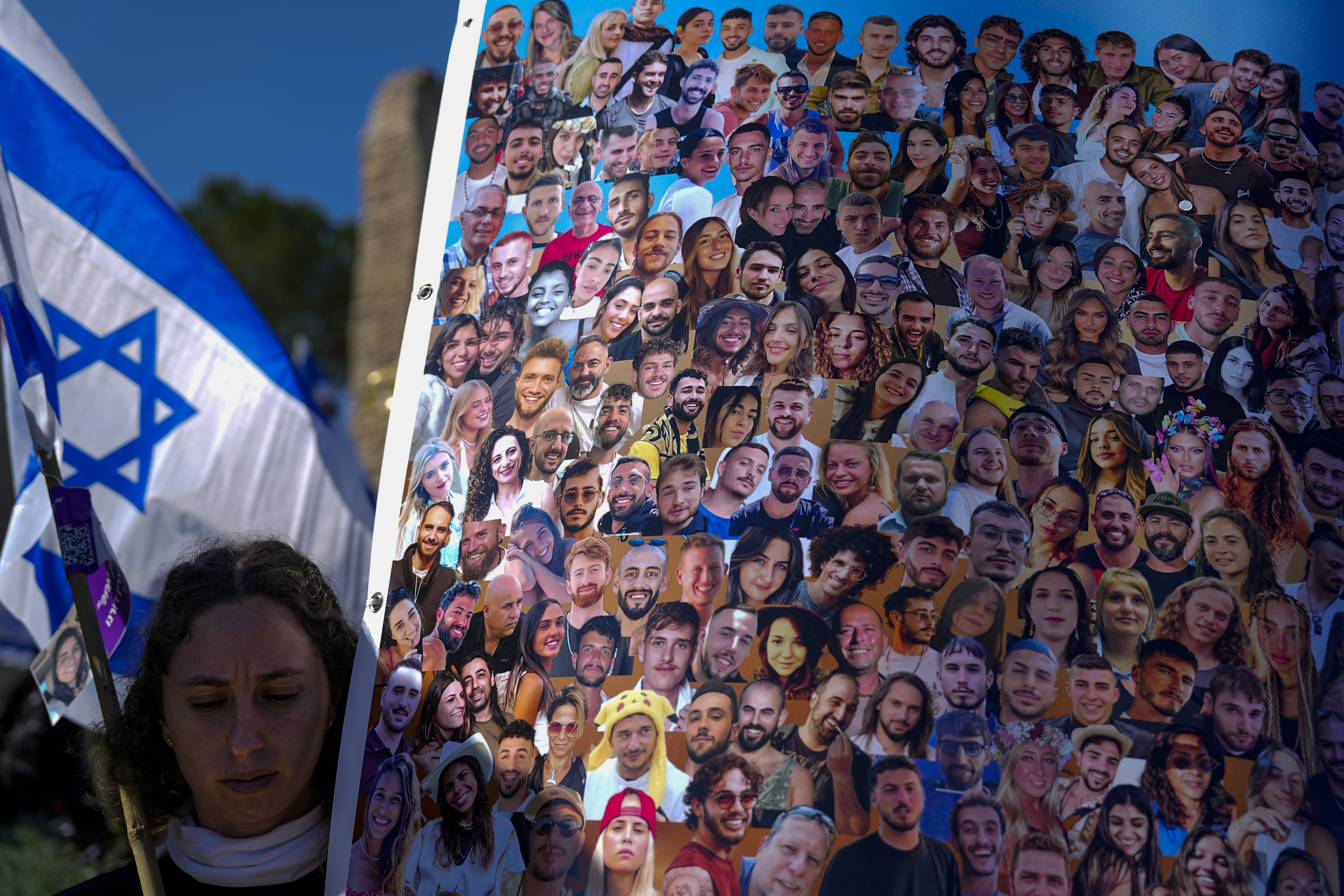 A woman holds a flag and a poster with pictures of revellers killed on October 7, 2023 at the Nova music festival by Hamas militants during a cross-border attack. Photo / AP
