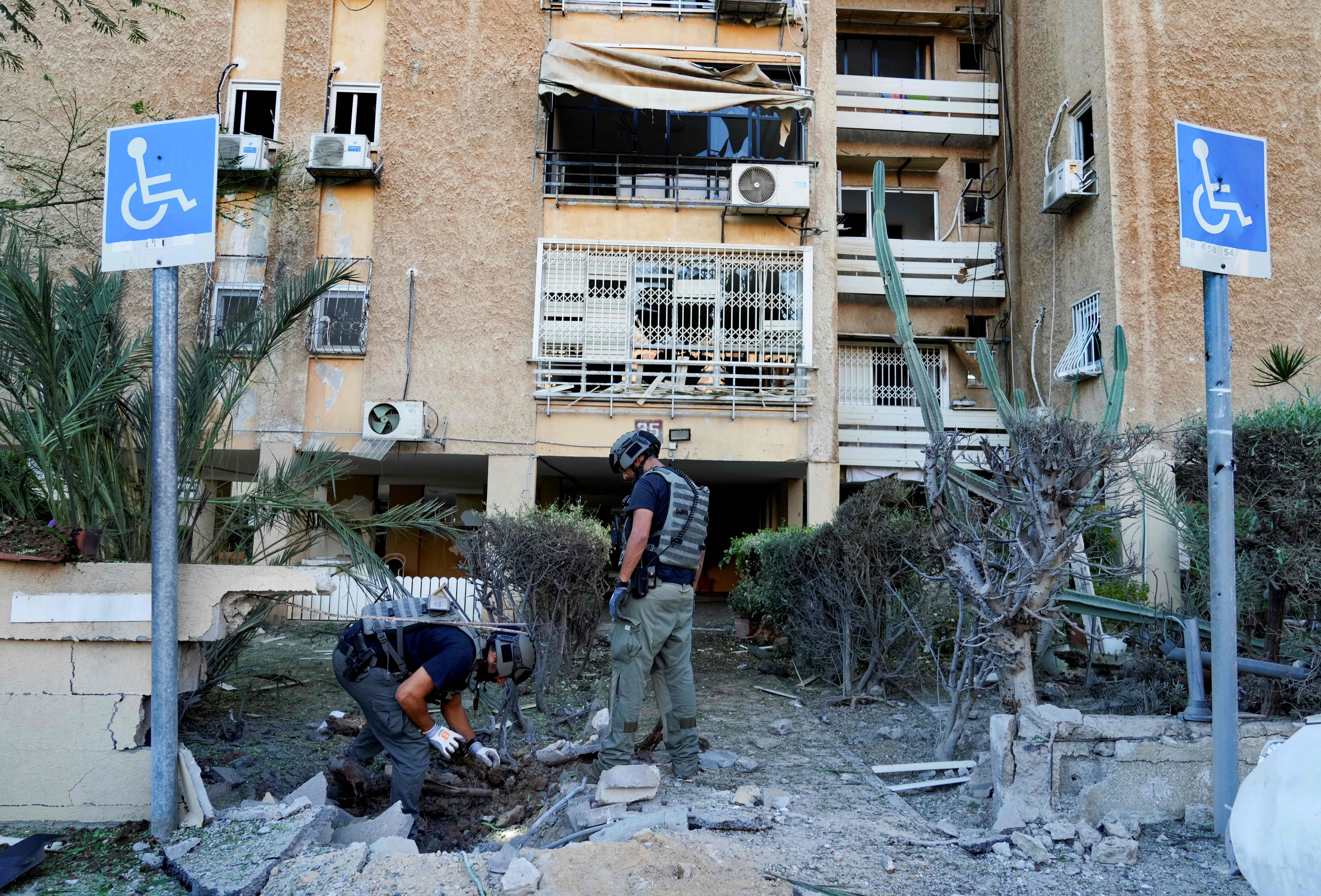 Members of Israeli bomb squad unit inspect a site hit by a rocket fired from the Gaza Strip, in Ashkelon. Photo / AP