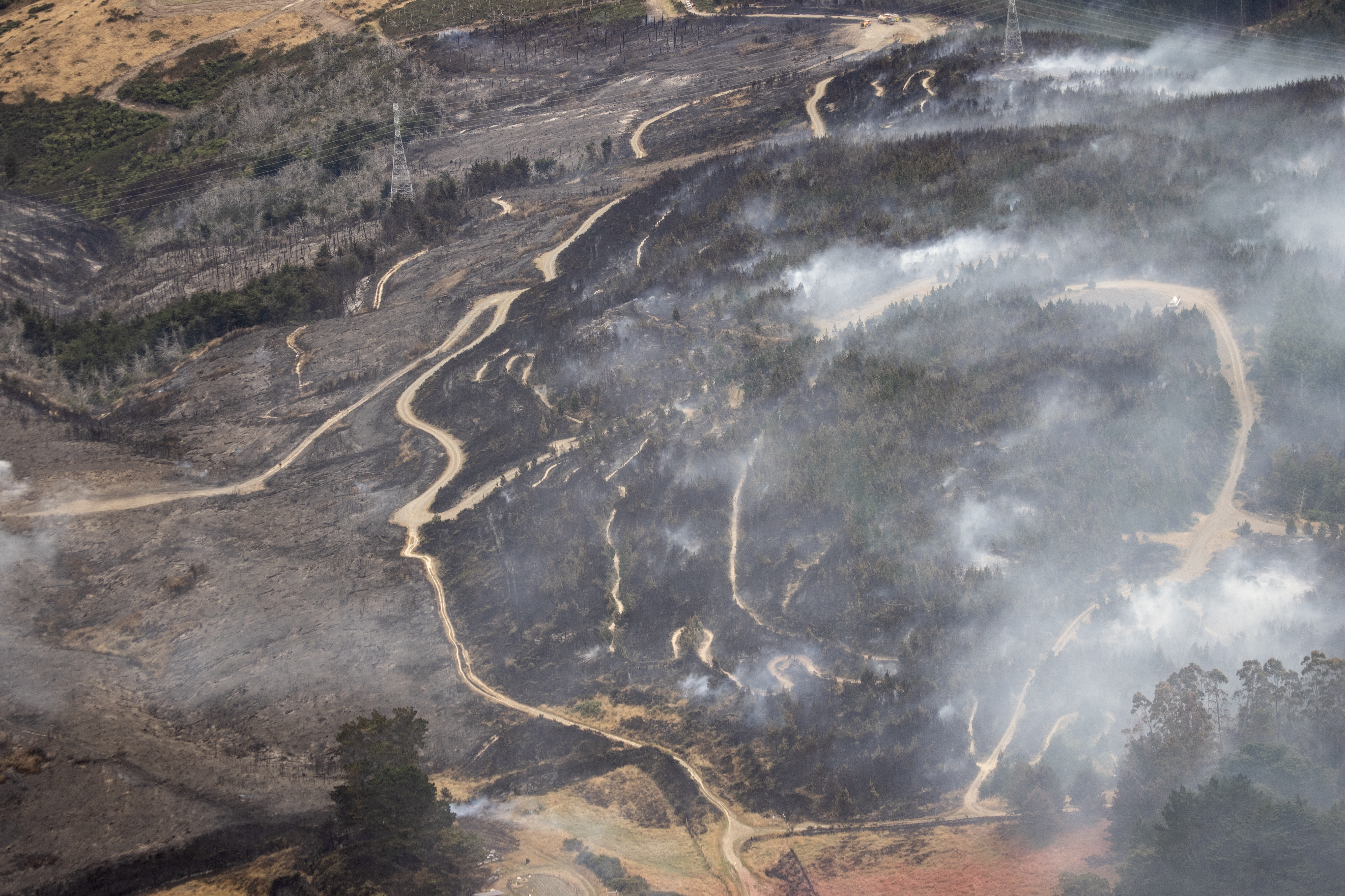 Smoke rises from a torched landscape on the Port Hills. Photo / George Heard