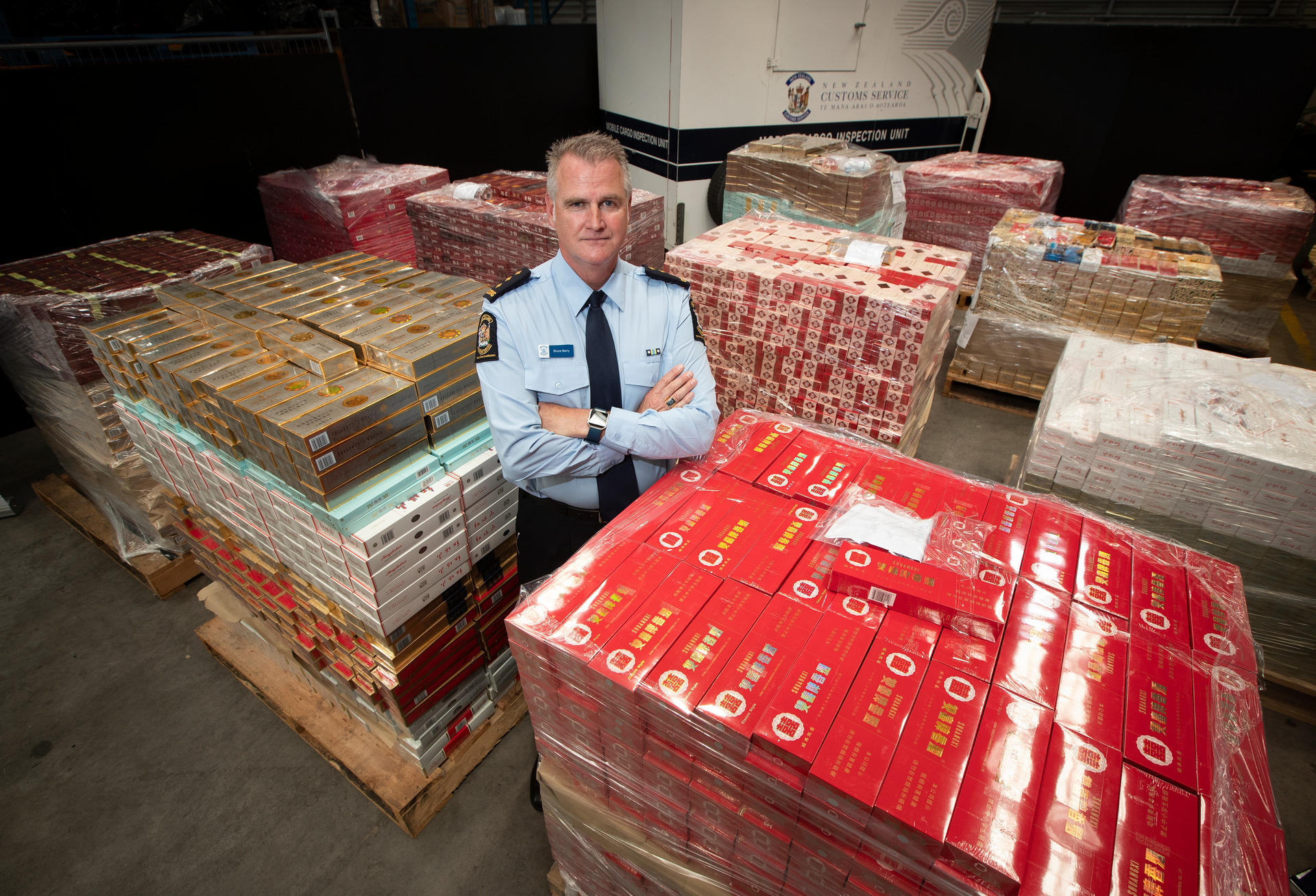 New Zealand Customs investigations manager Bruce Berry with some of the smuggled cigarettes seized during Operation Whitethorn. Photo / Brett Phibbs